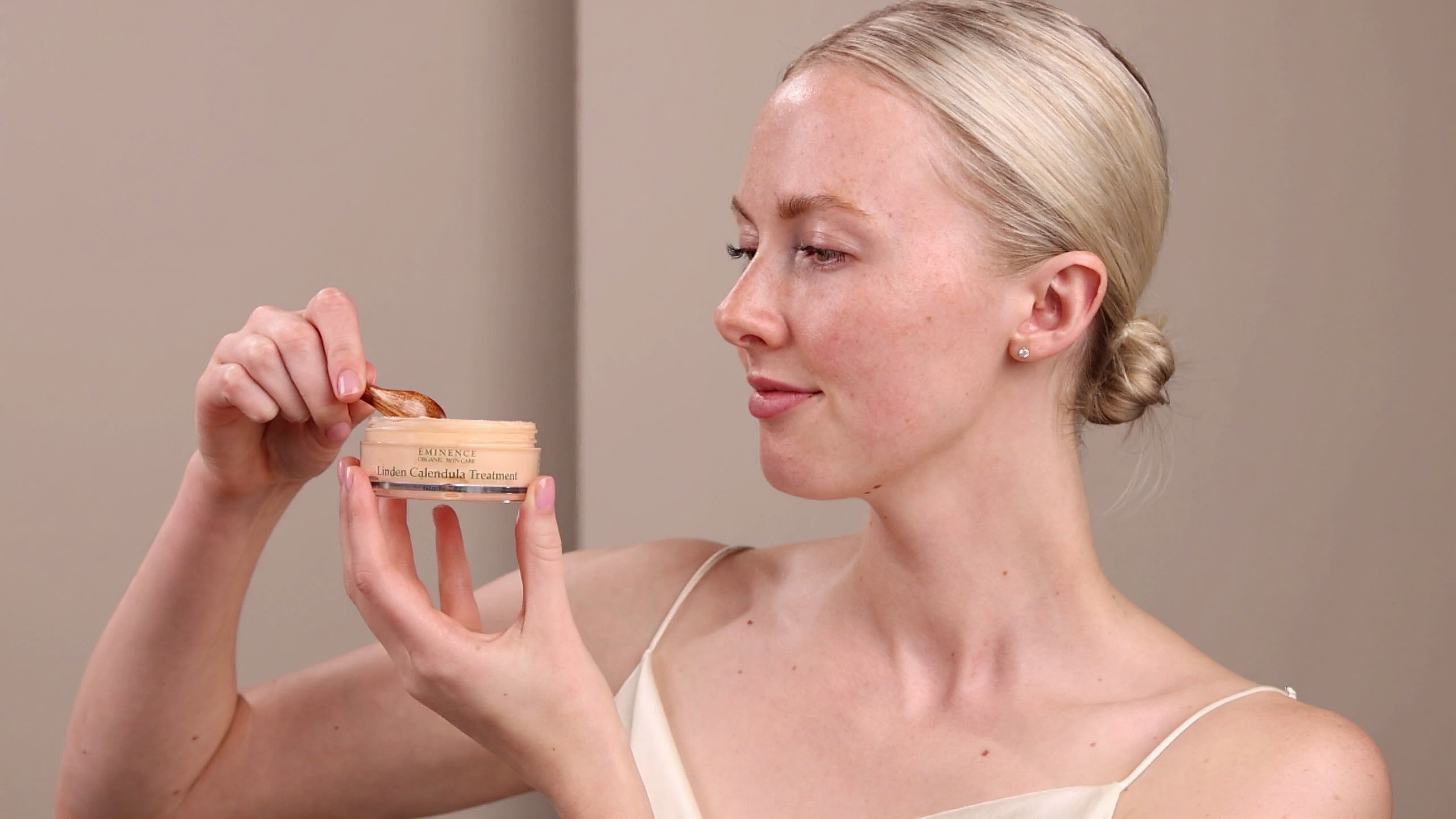 A woman holding the Eminence Organics Linden Calendula Treatment Jar