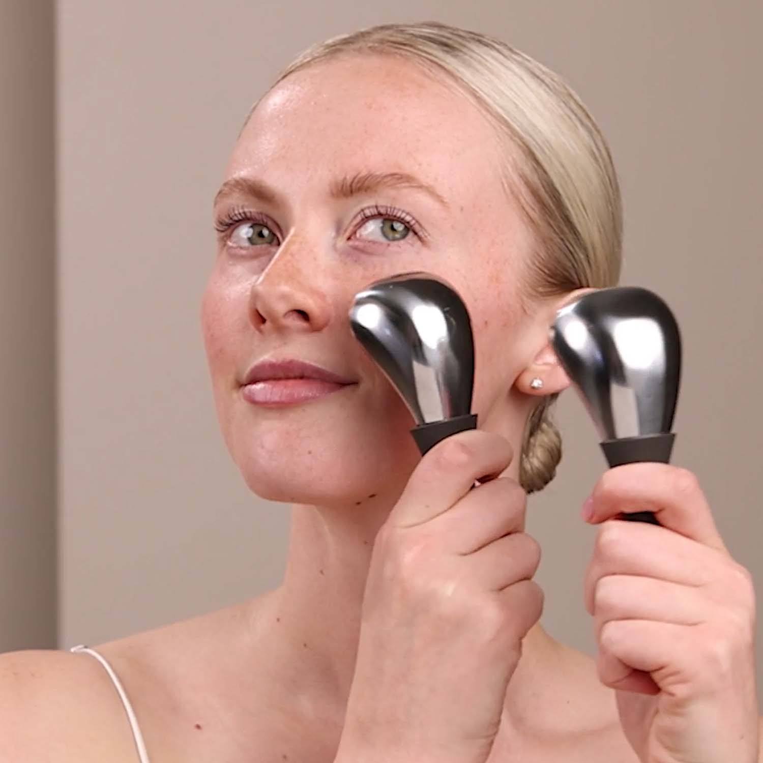 A woman using the Eminence Organics Cryo-Thermal Sculpting Tool on her face