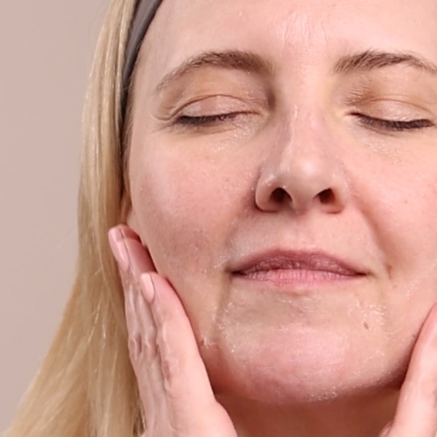 A woman washing her face with the Eminence Organics Firm Skin Acai Cleanser