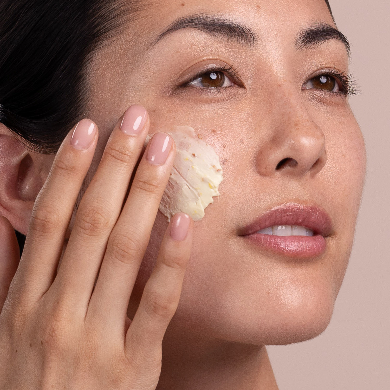 A woman applying Eminence Organics Calm Skin Arnica Masque to face