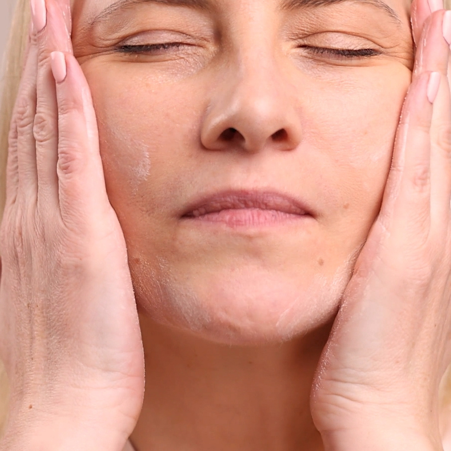 A woman applying the Eminence Organics Linden Calendula Treatment to her face with both hands