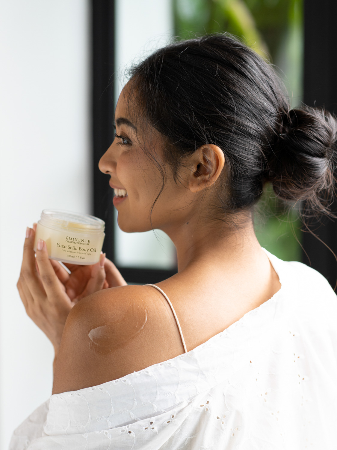 A woman holding the Eminence Organics Yuzu Solid Body Oil