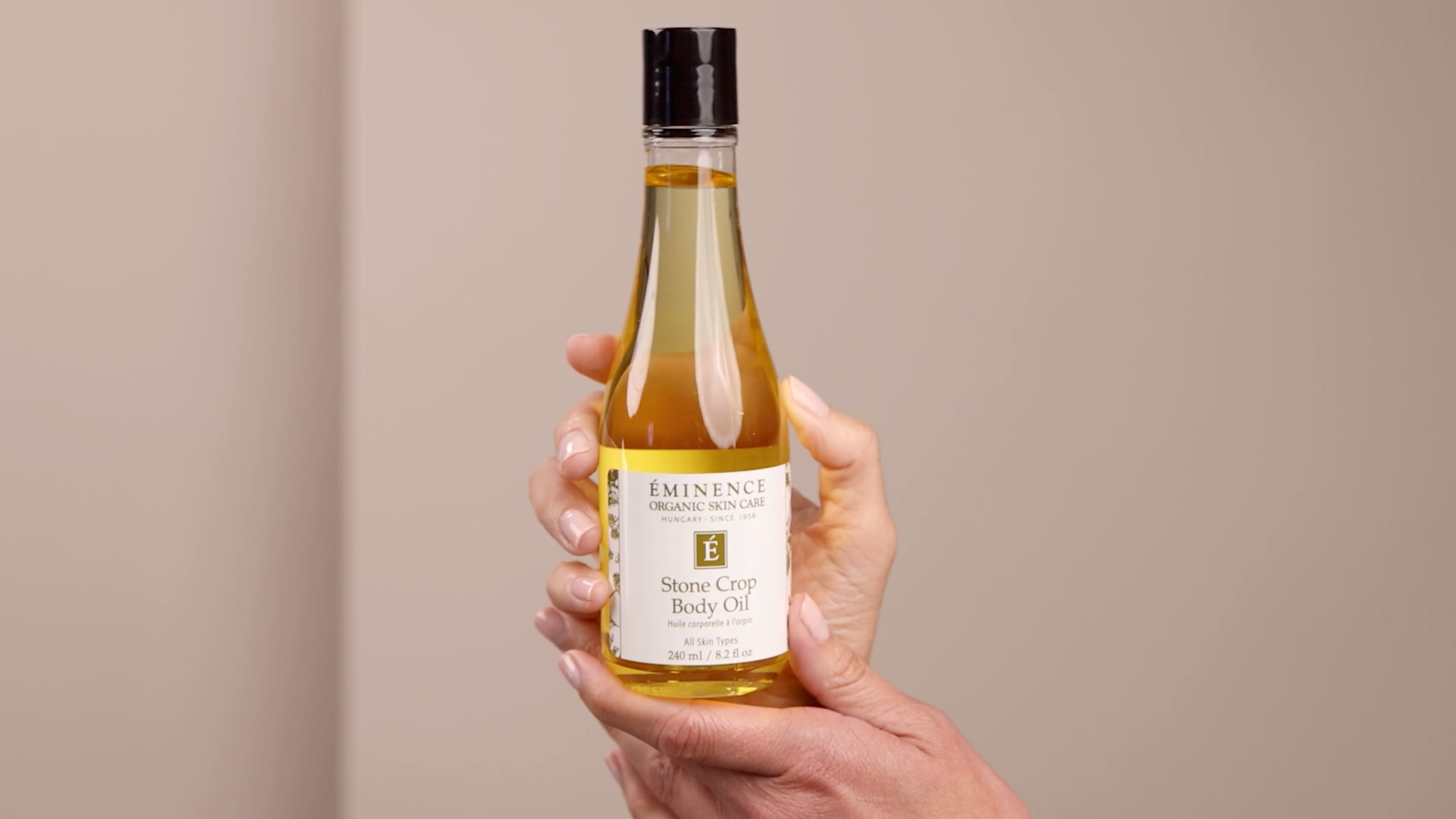 Hands holding the Eminence Organics Stone Crop Body Oil