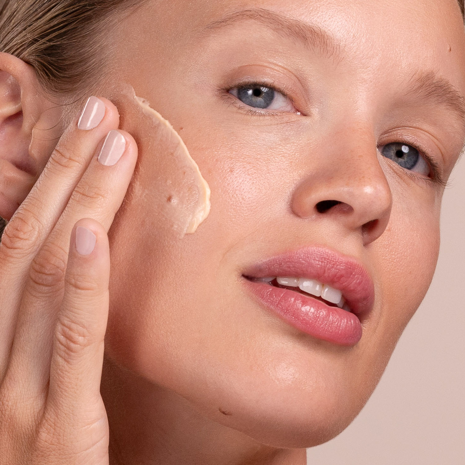 A woman applying Eminence Organics Apricot Whip Moisturizer on face