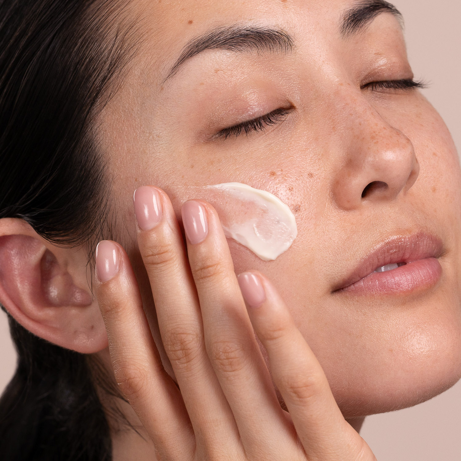A woman applying Eminence Organics Apricot Calendula Nourishing Cream