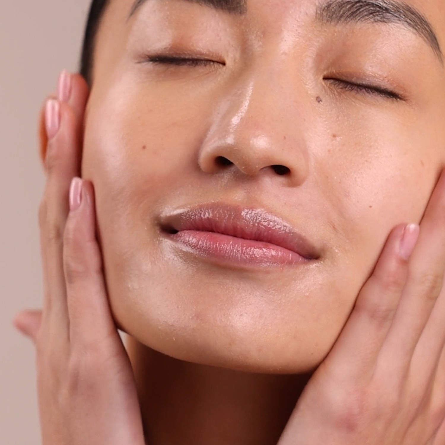 A woman applying the Eminence Organics Strawberry Rhubarb Hyaluronic Hydrator on her face