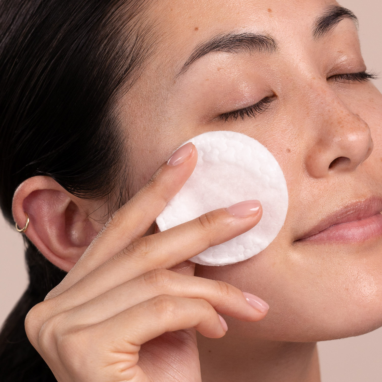 A woman applying the Eminence Organics Firm Skin Acai Exfoliating Peel to her face