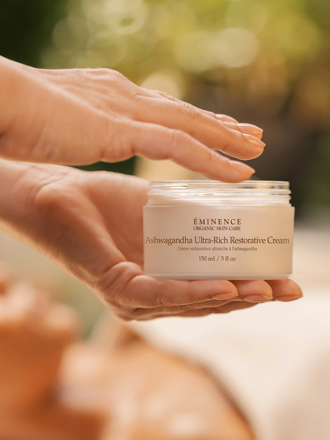 A woman holding the Eminence Organics Ashwagandha Ultra-Rich Restorative Cream 