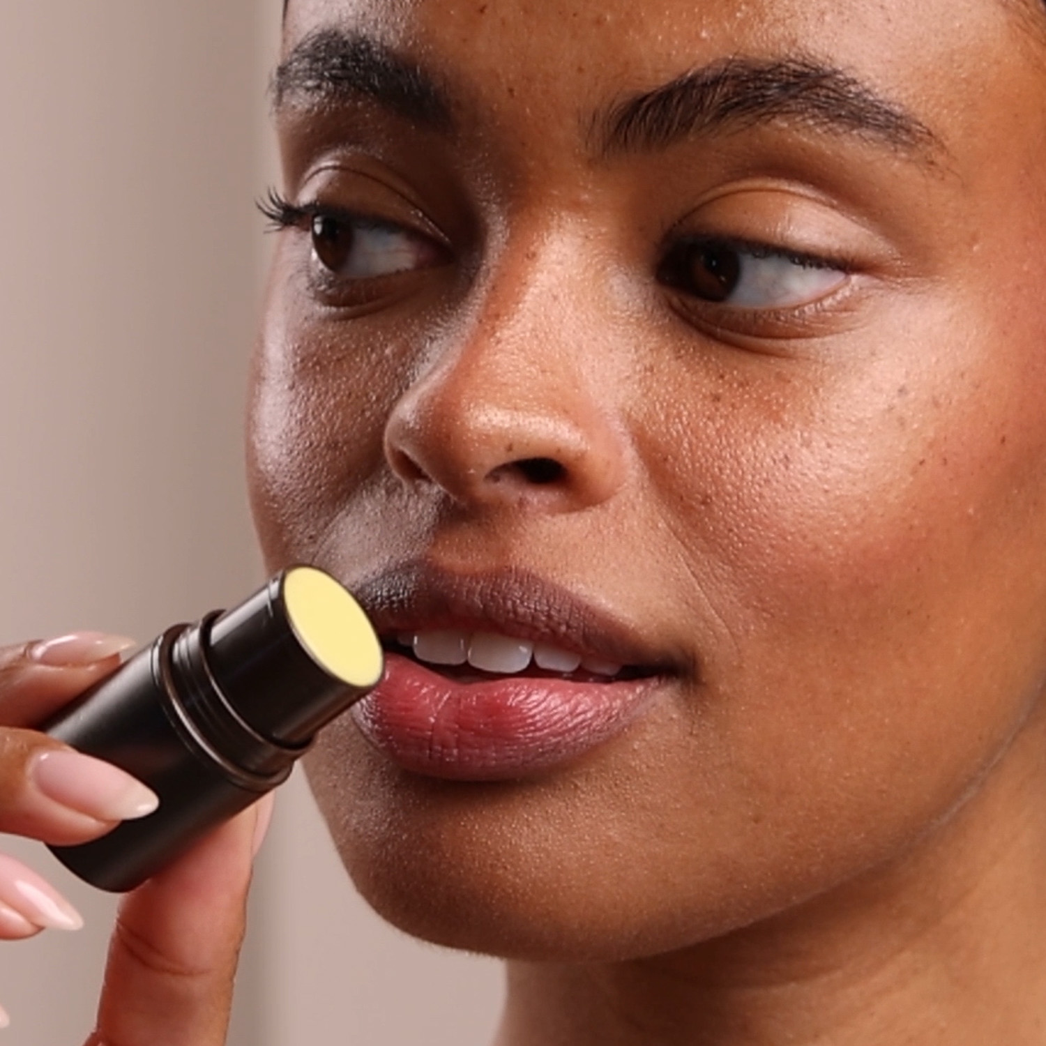 A woman applying the Eminence Organics Rosehip & Lemongrass Lip Balm SPF 15 on her lips