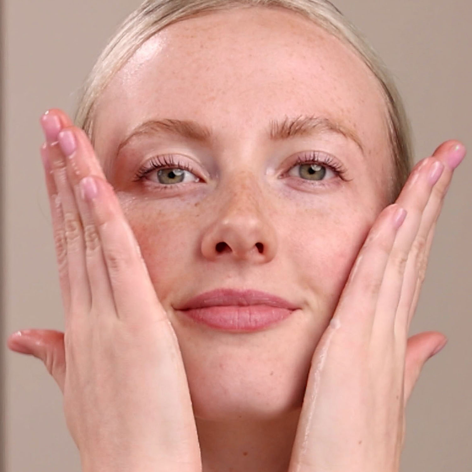 A woman applying Eminence Organics Charcoal Exfoliating Gel Cleanser to face