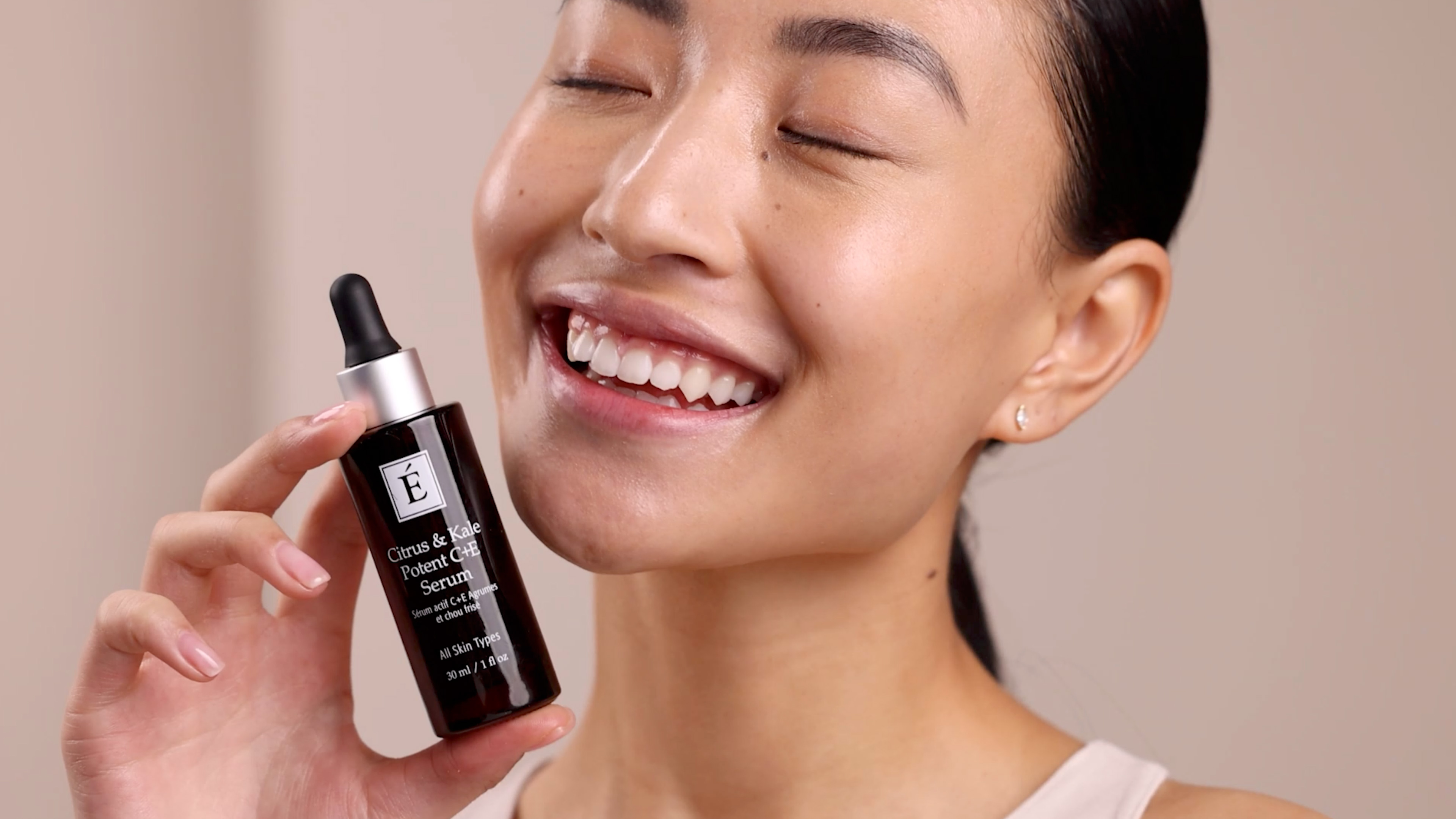 A woman holding Eminence Organics Citrus & Kale Potent C+E Serum