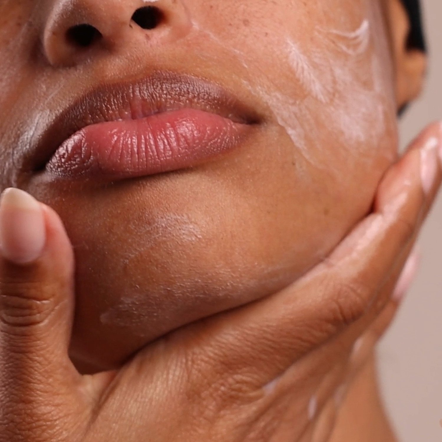 A woman applying the Eminence Organics Strawberry Rhubarb Masque on her face