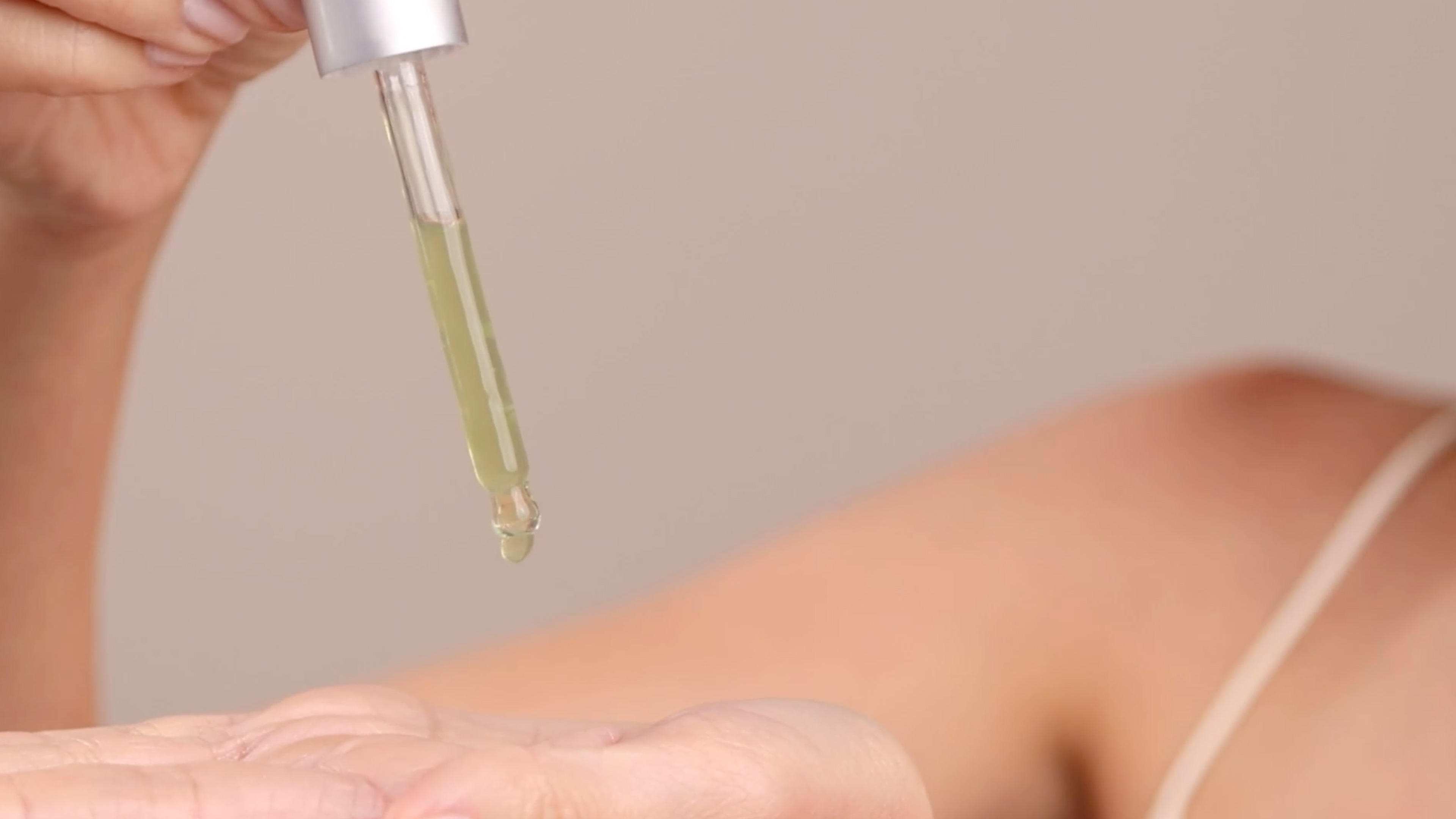 A woman holding a dropper filled with Eminence Organics Stone Crop Serum