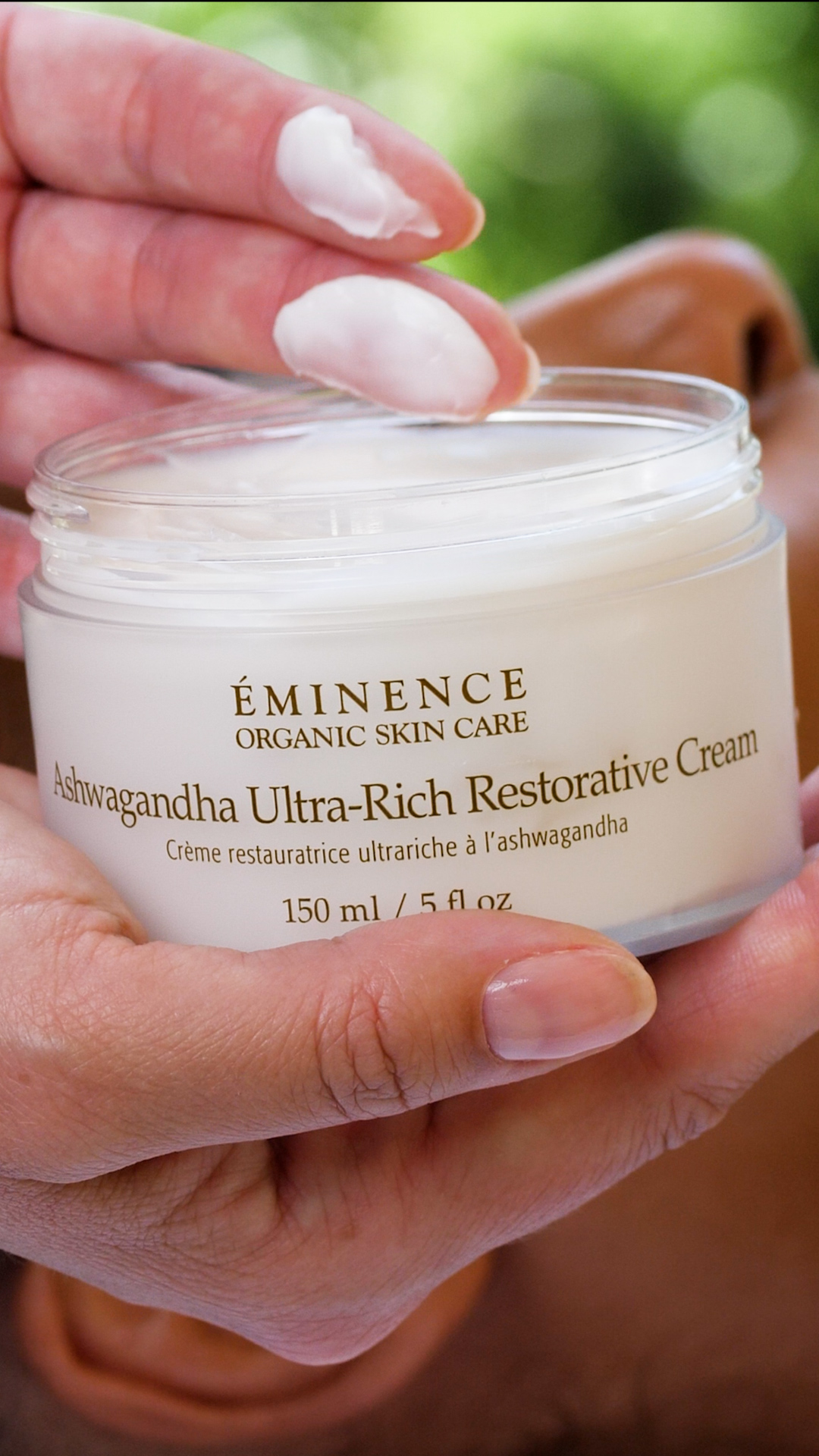A woman holding the Eminence Organics Ashwagandha Ultra-Rich Restorative Cream 