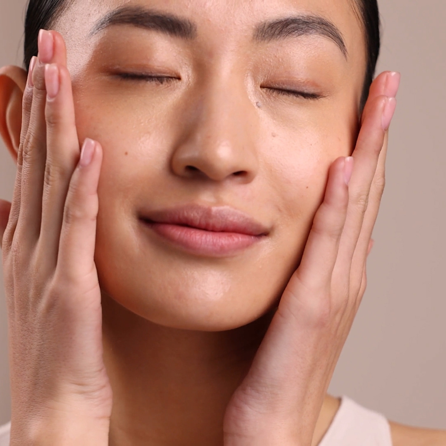 A woman applying Eminence Organics Citrus & Kale Potent C+E Serum to face