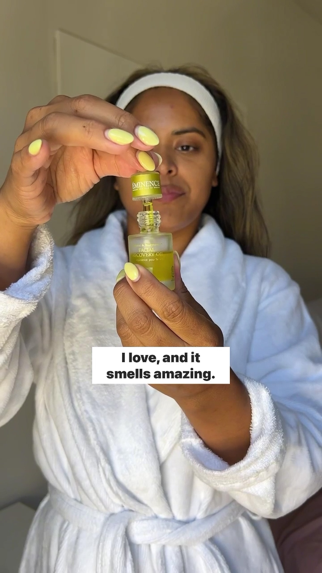 A woman opening the Eminence Organics Facial Recovery Oil glass bottle