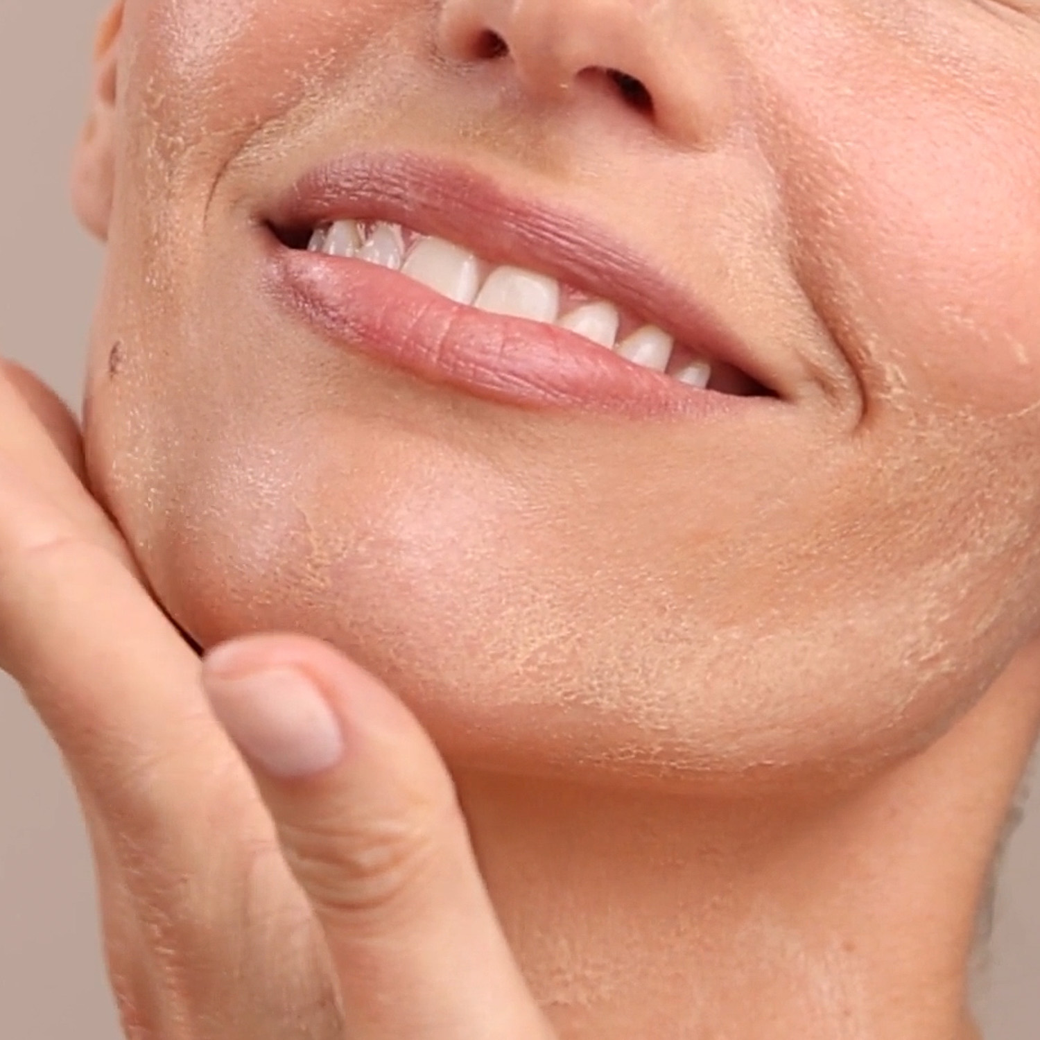 A close up of a woman applying the Eminence Organics Mango Exfoliating Enzyme Masque to their face