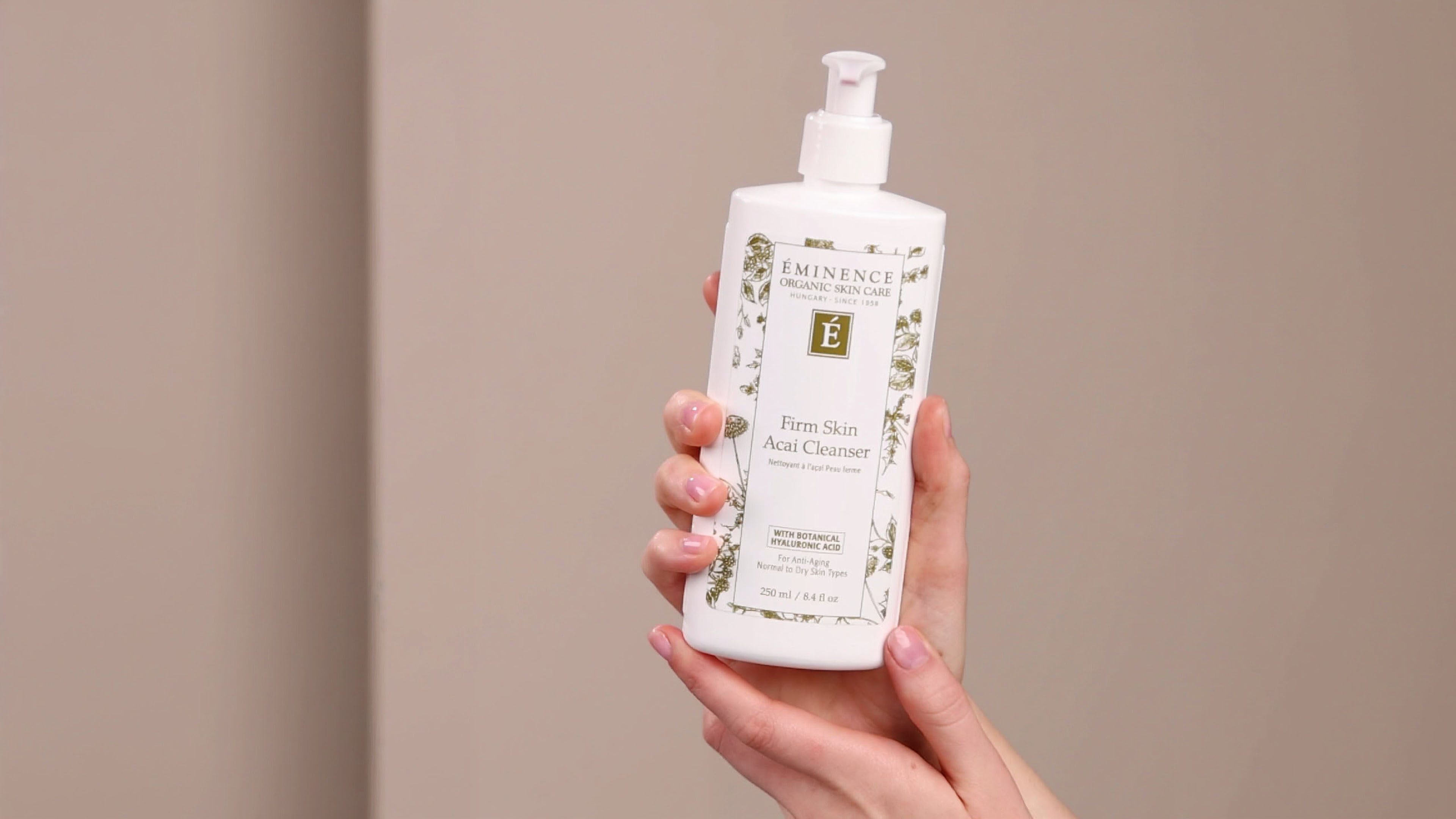 A woman applying the Eminence Organics Firm Skin Acai Cleanser on the palm of her hand