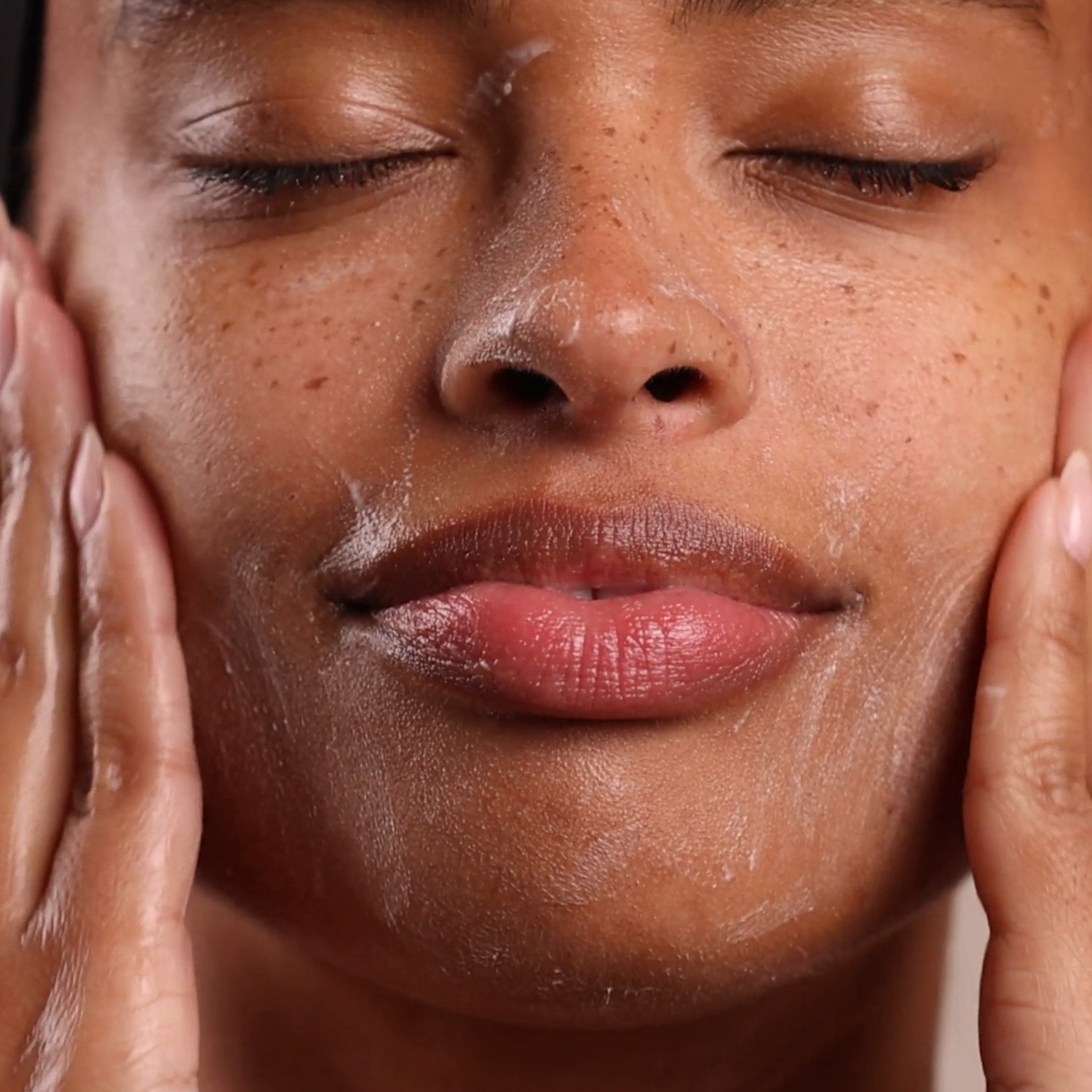A woman applying Eminence Organics Age Corrective Starter Set on face