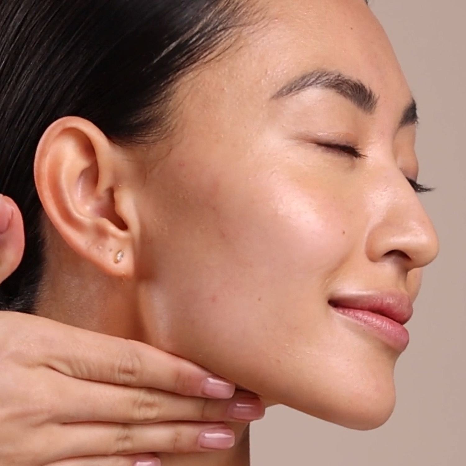 A woman applying Eminence Organics Eight Greens Youth Serum to face