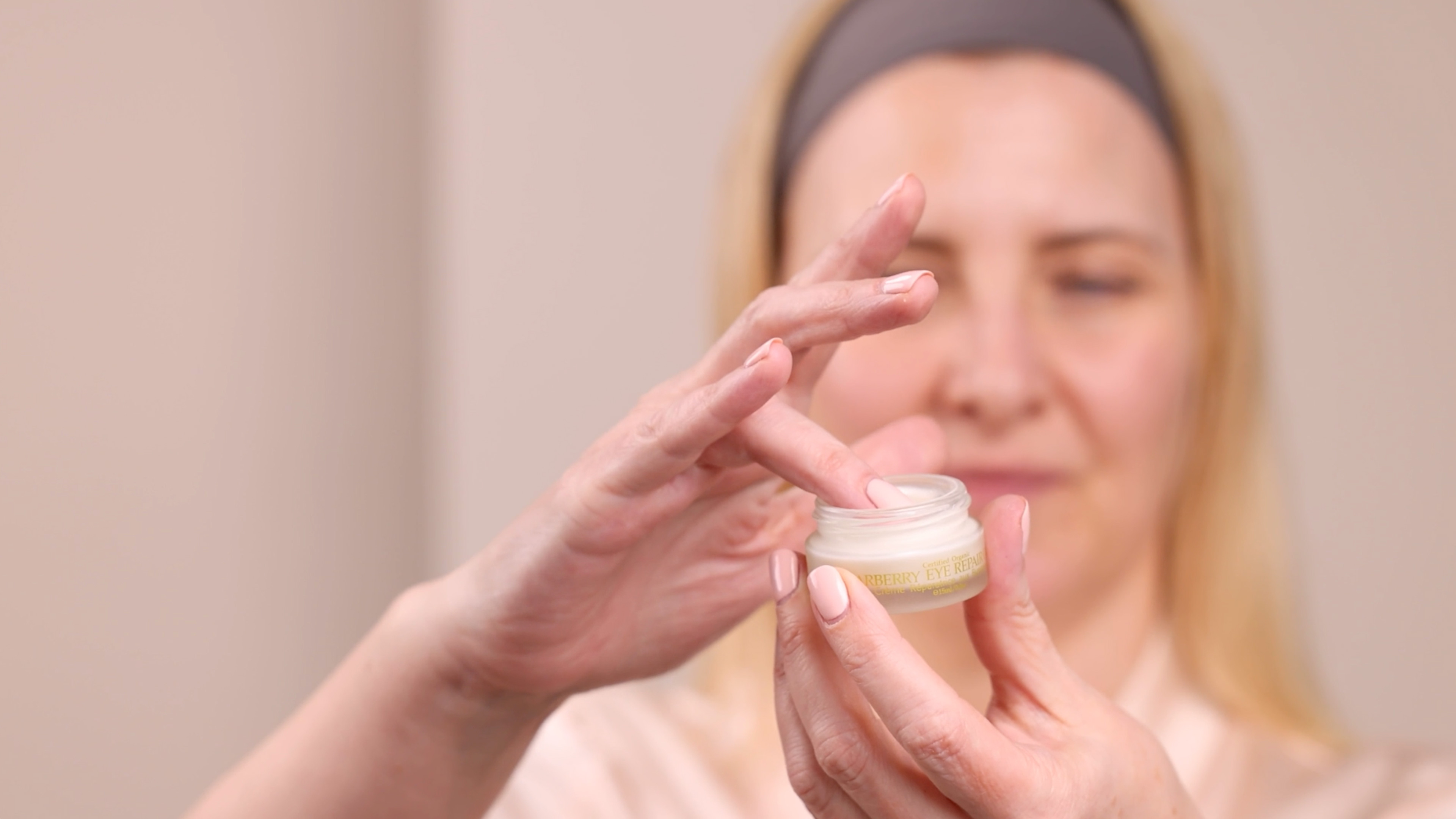 A woman holding Eminence Organics Bearberry Eye Repair Cream