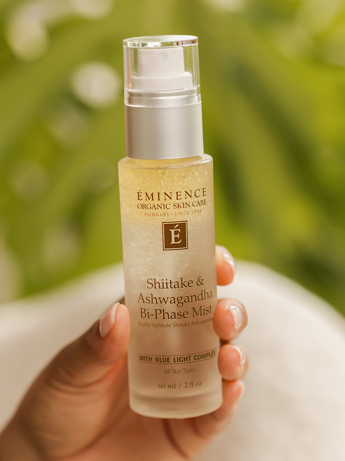 A woman holding Eminence Organics Shiitake & Ashwagandha Bi-Phase Mist 