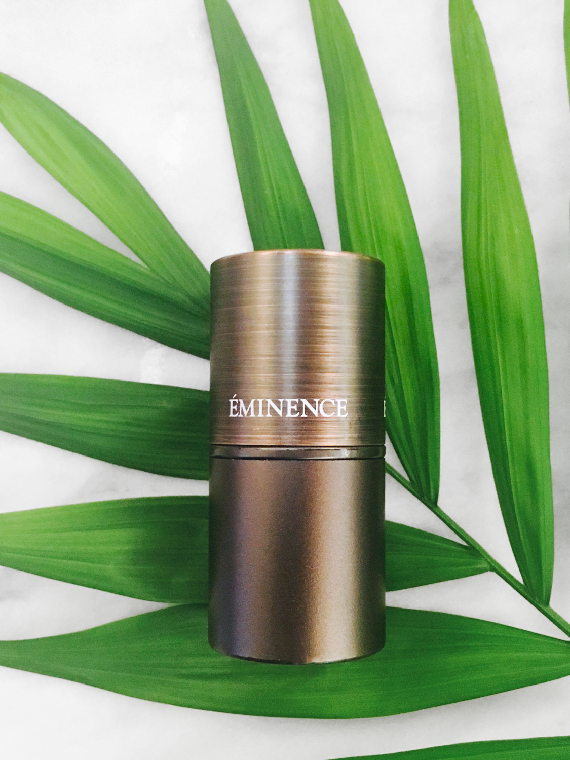 Eminence Organics Rosehip & Lemongrass Lip Balm SPF 15 on background of green leaves