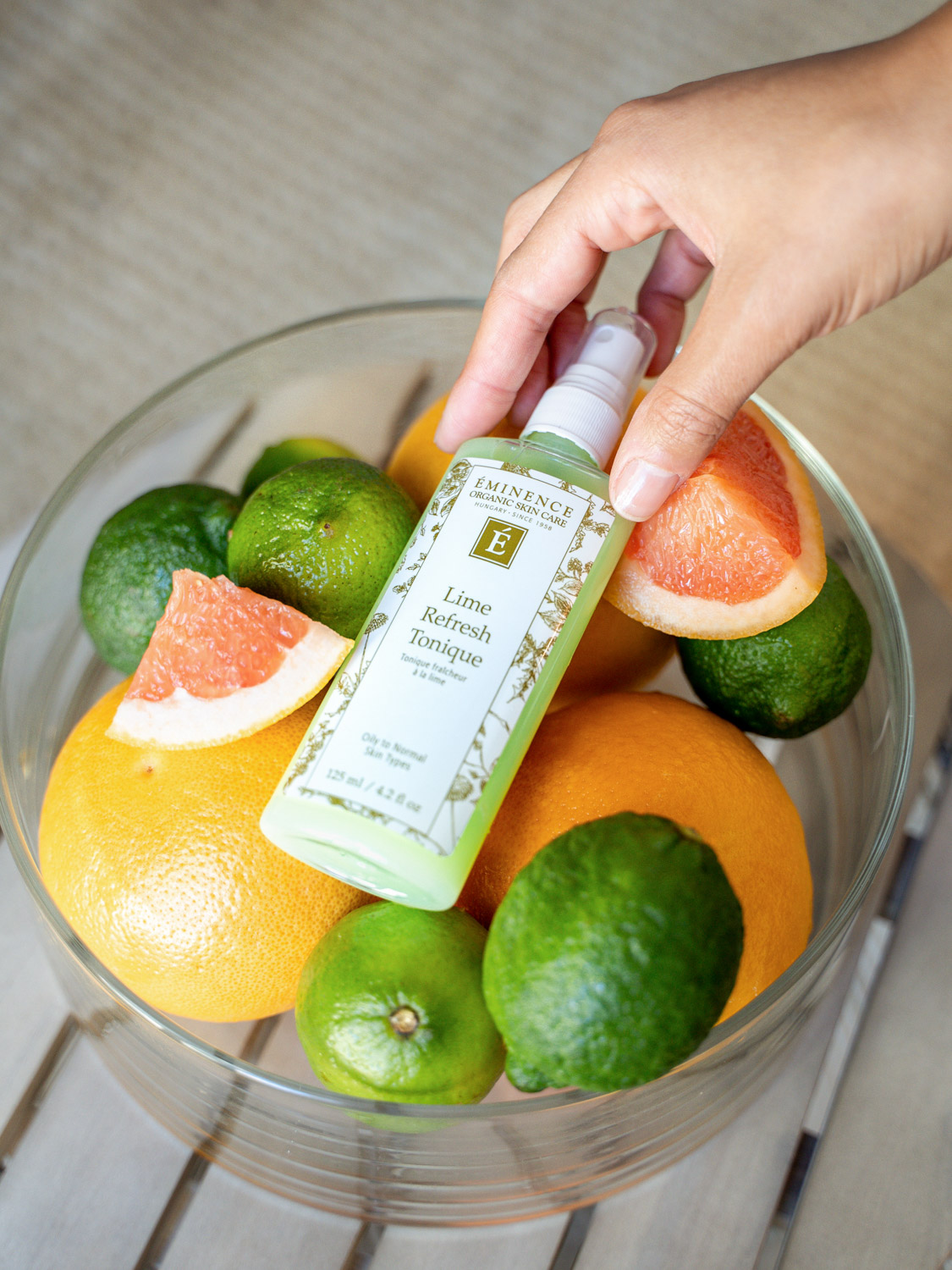 The Eminence Organics Lime Refresh Tonique bottle surrounded by fruits