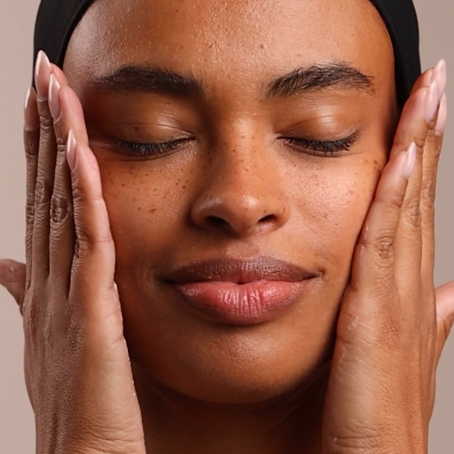 A woman applying the Eminence Organics Strawberry Rhubarb Hyaluronic Serum on her face
