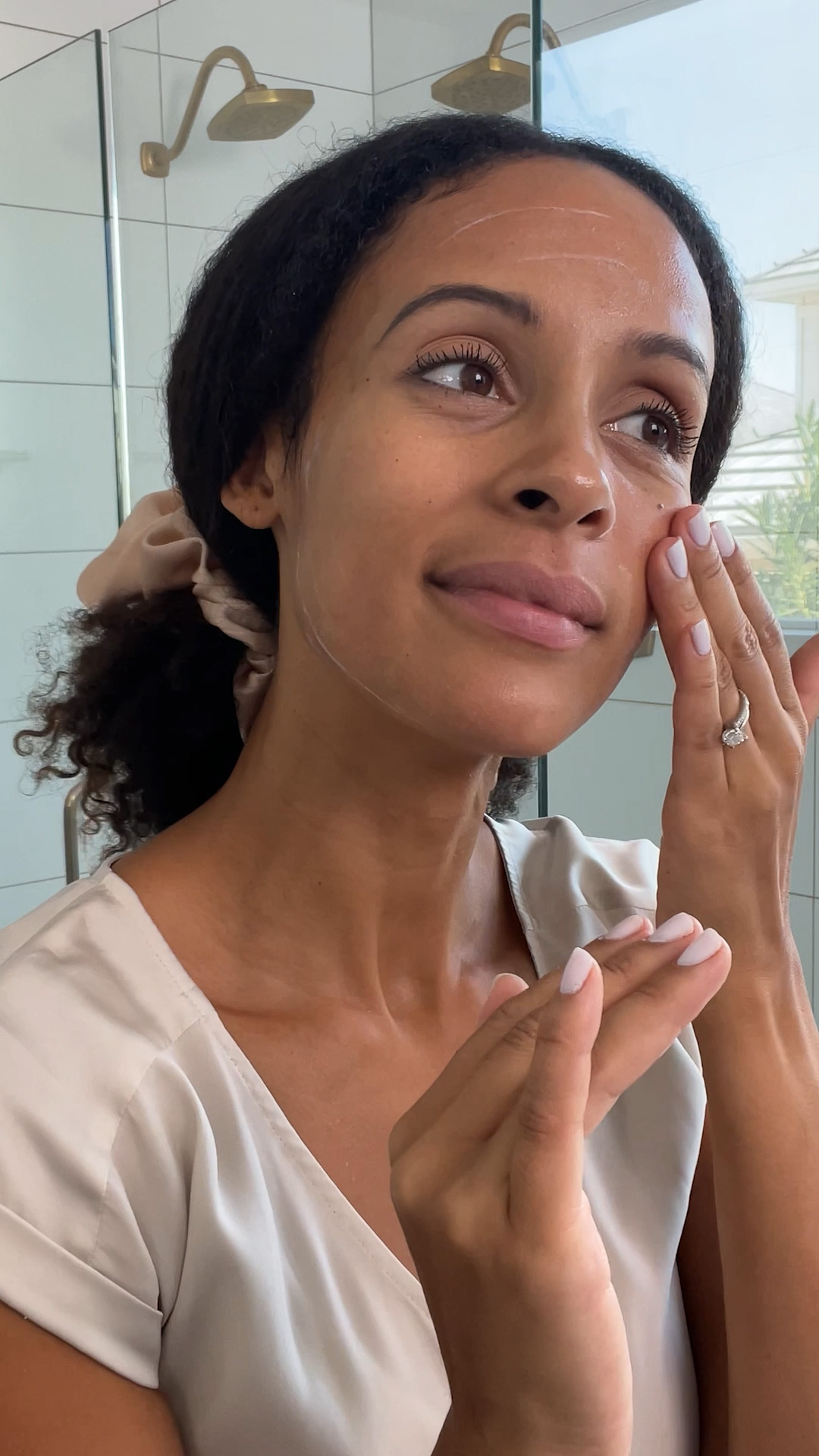 A woman applying Eminence Organics Acne Advanced 3-Step Treatment System on face