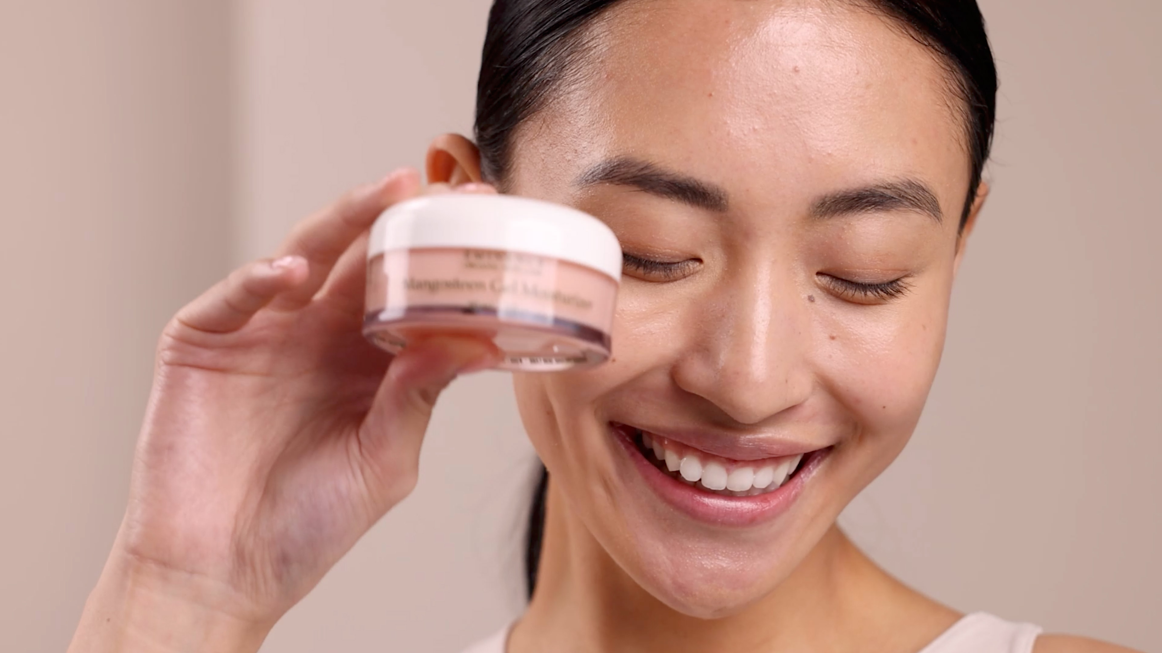 A woman holding the Eminence Organics Mangosteen Gel Moisturizer Jar