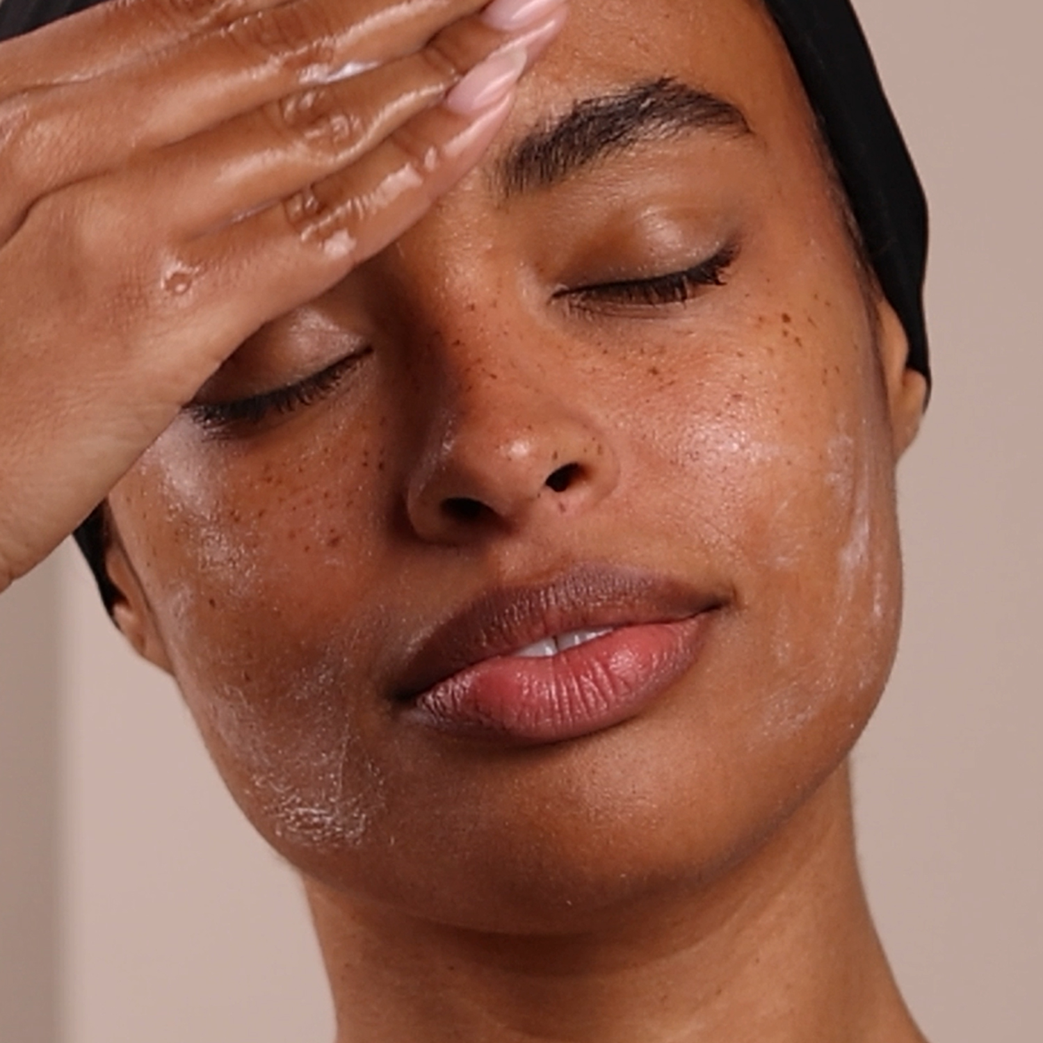 A woman applying the Eminence Organics Coconut Milk Cleanser to her forehead