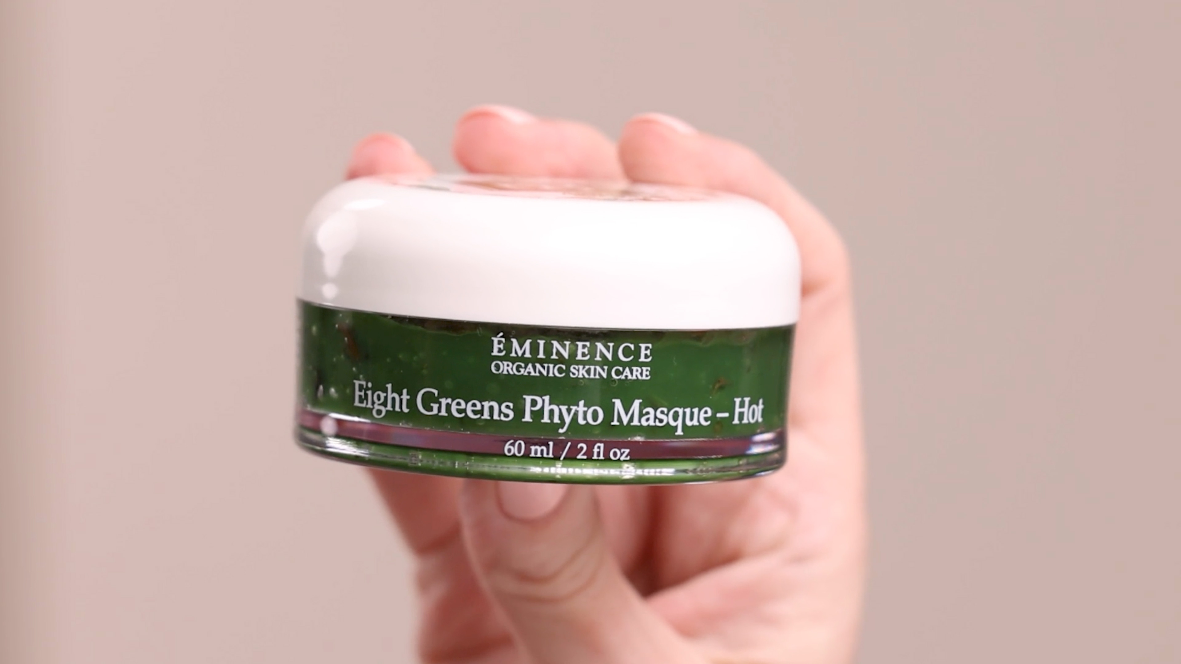 A hand holding the Eminence Organics Eight Greens Phyto Masque – Hot jar