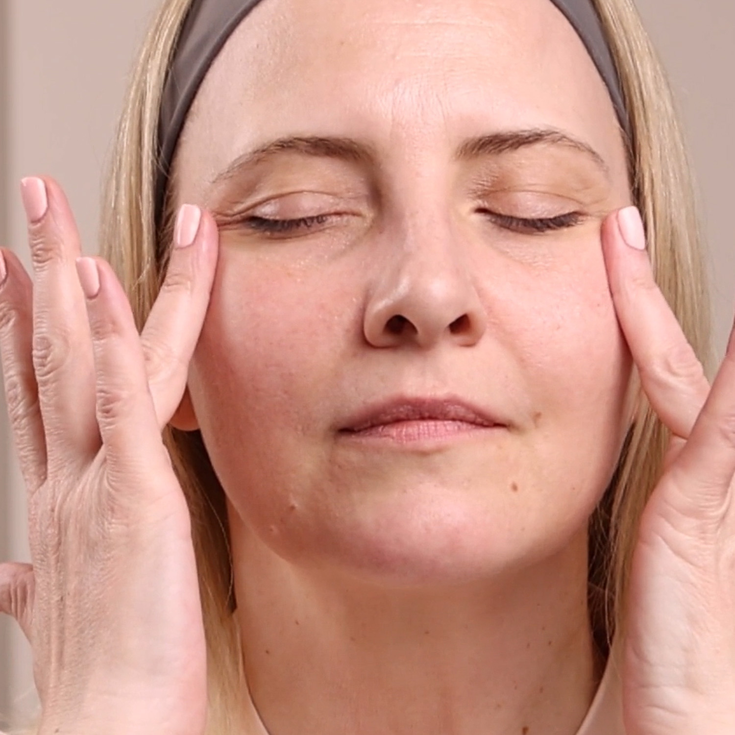 A woman applying the Eminence Organics Wild Plum Eye Cream Swatch under her eyes