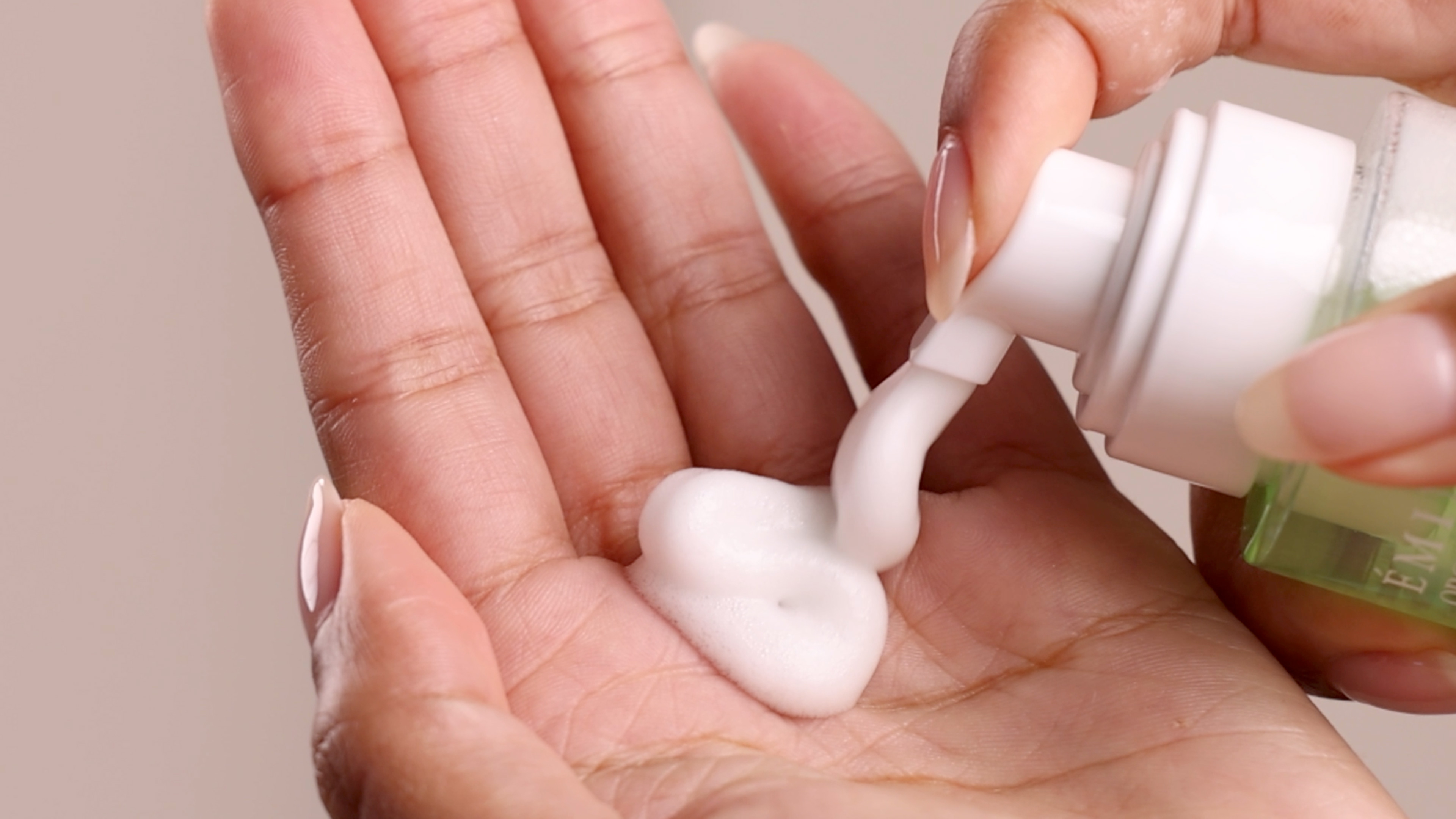 A woman applying Eminence Organics Acne Advanced Cleansing Foam on hand