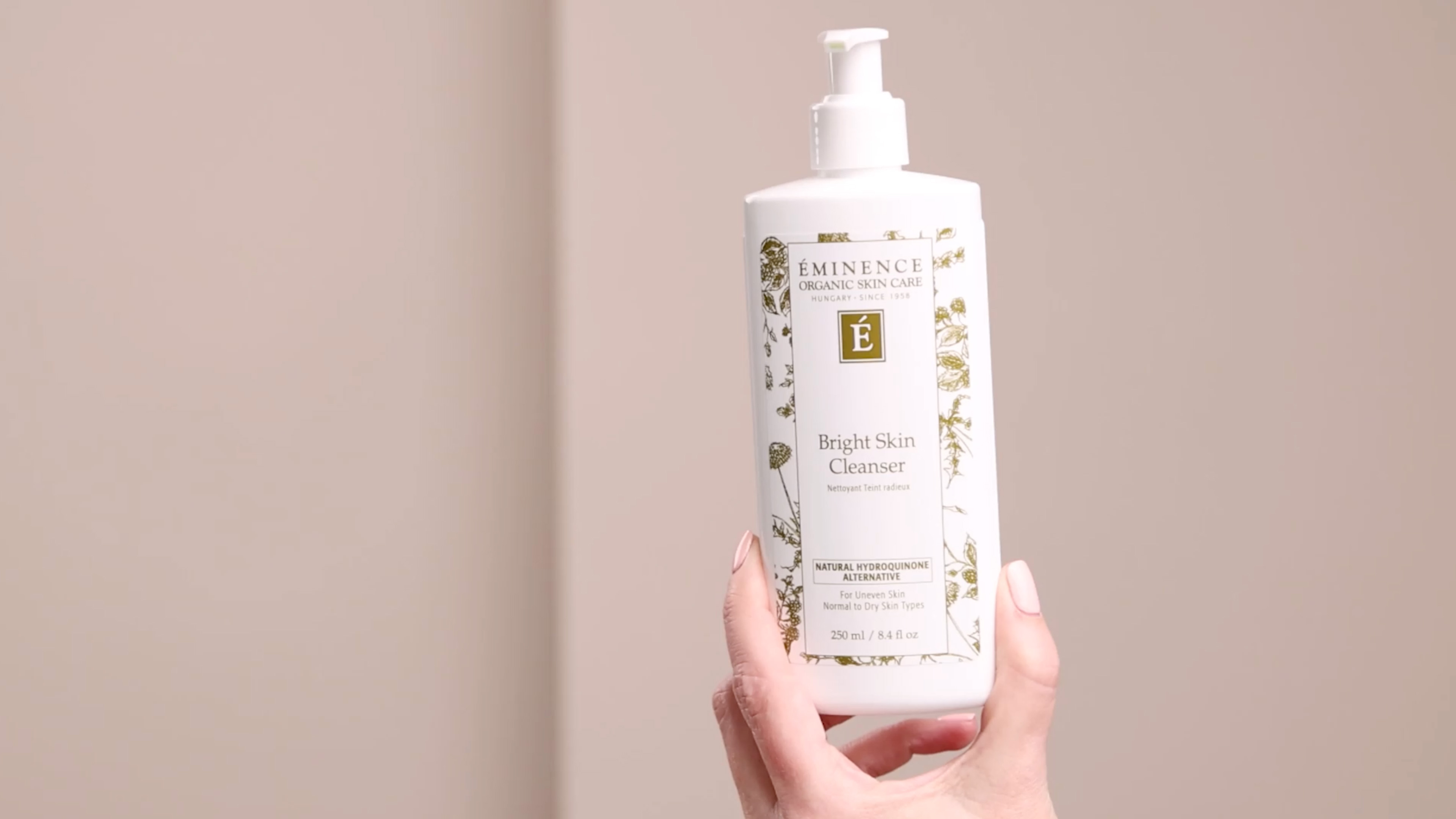 A woman holding Eminence Organics Bright Skin Cleanser