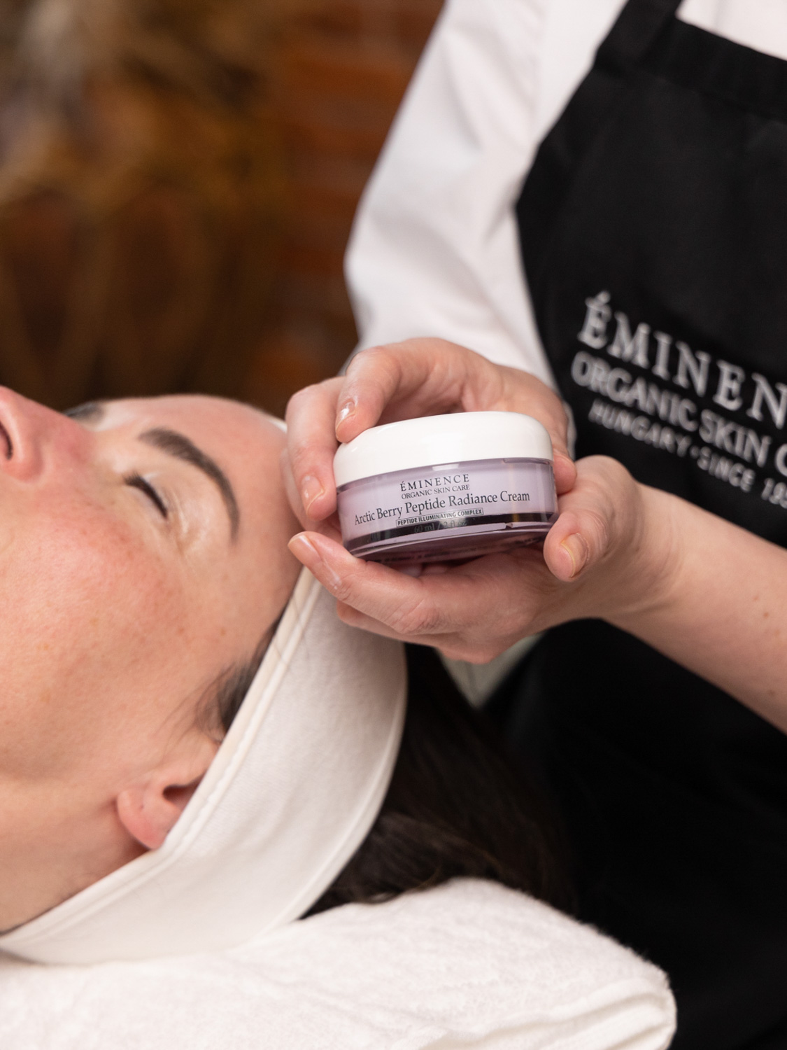 An esthetician holding Eminence Organics Arctic Berry Radiance Cream
