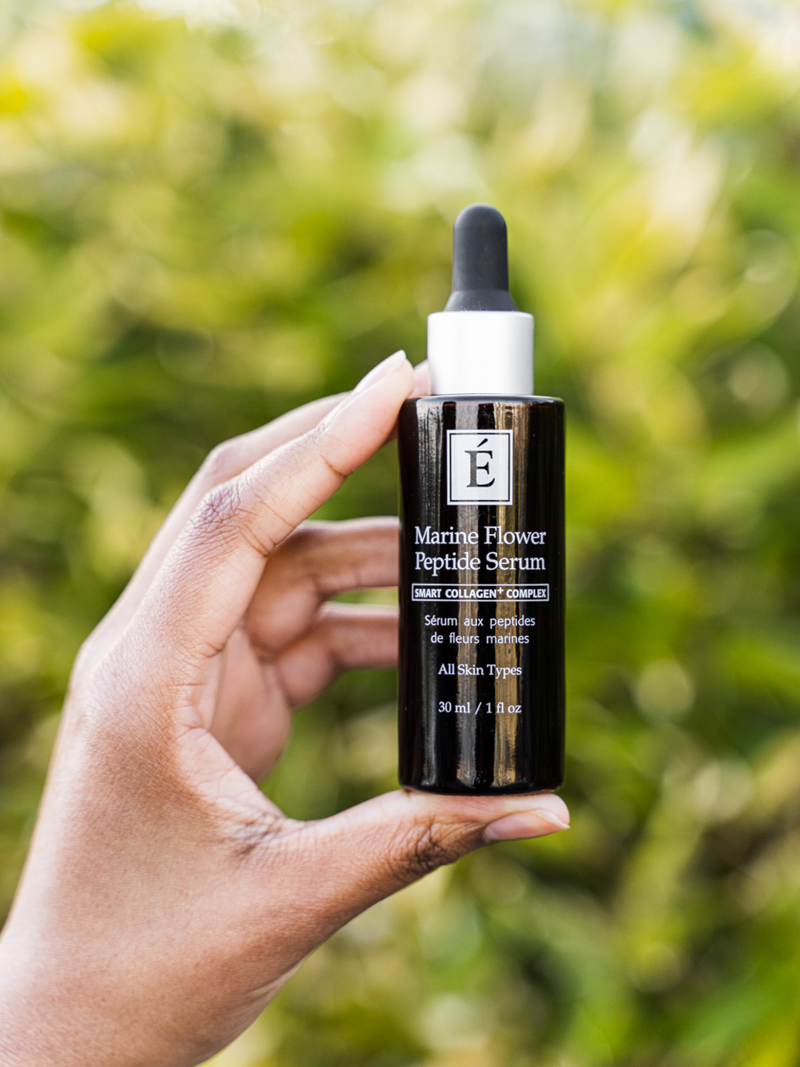 A hand holding the Eminence Organics Marine Flower Peptide Serum