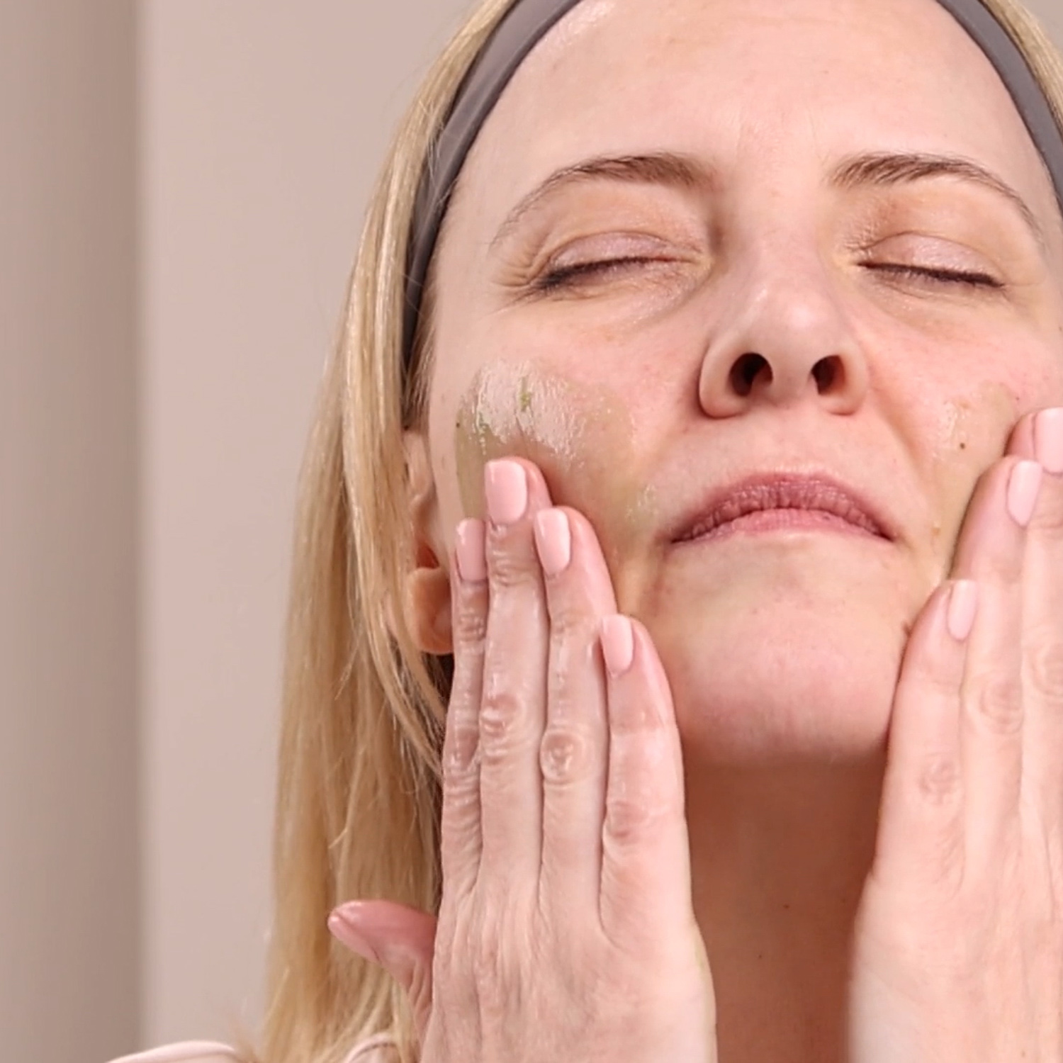 A woman applying the Eminence Organics Eight Greens Phyto Masque – Hot to her face