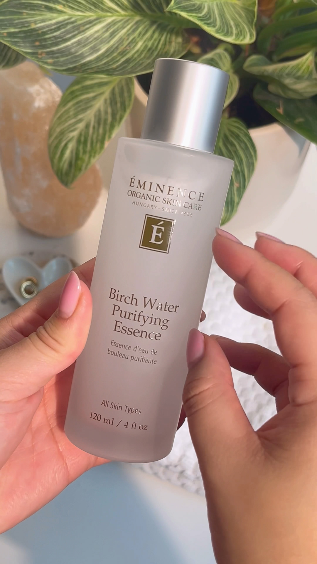 A woman holding Eminence Organics Birch Water Purifying Essence