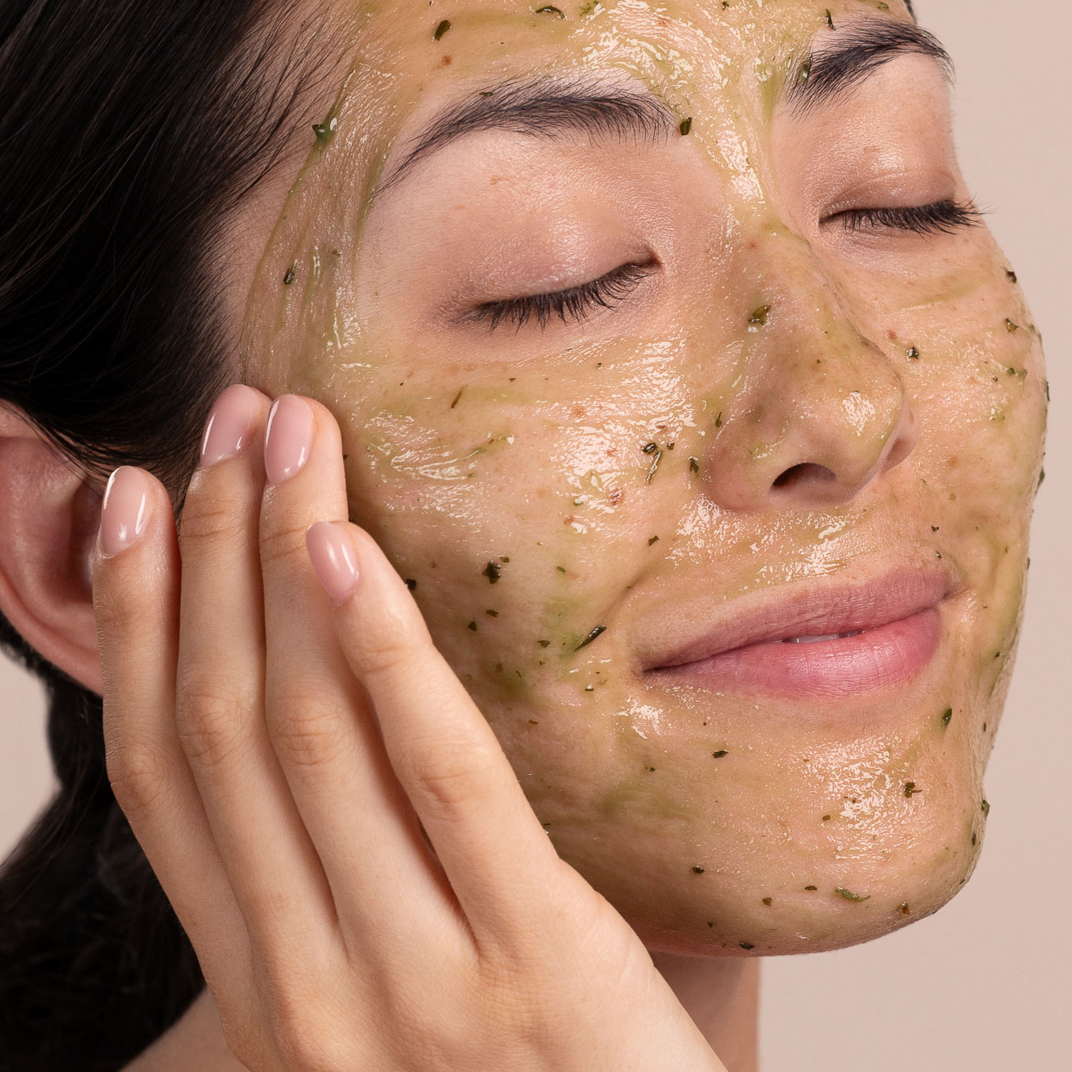 A woman applying the Eminence Organics Eight Greens Phyto Masque – Not Hot to her face