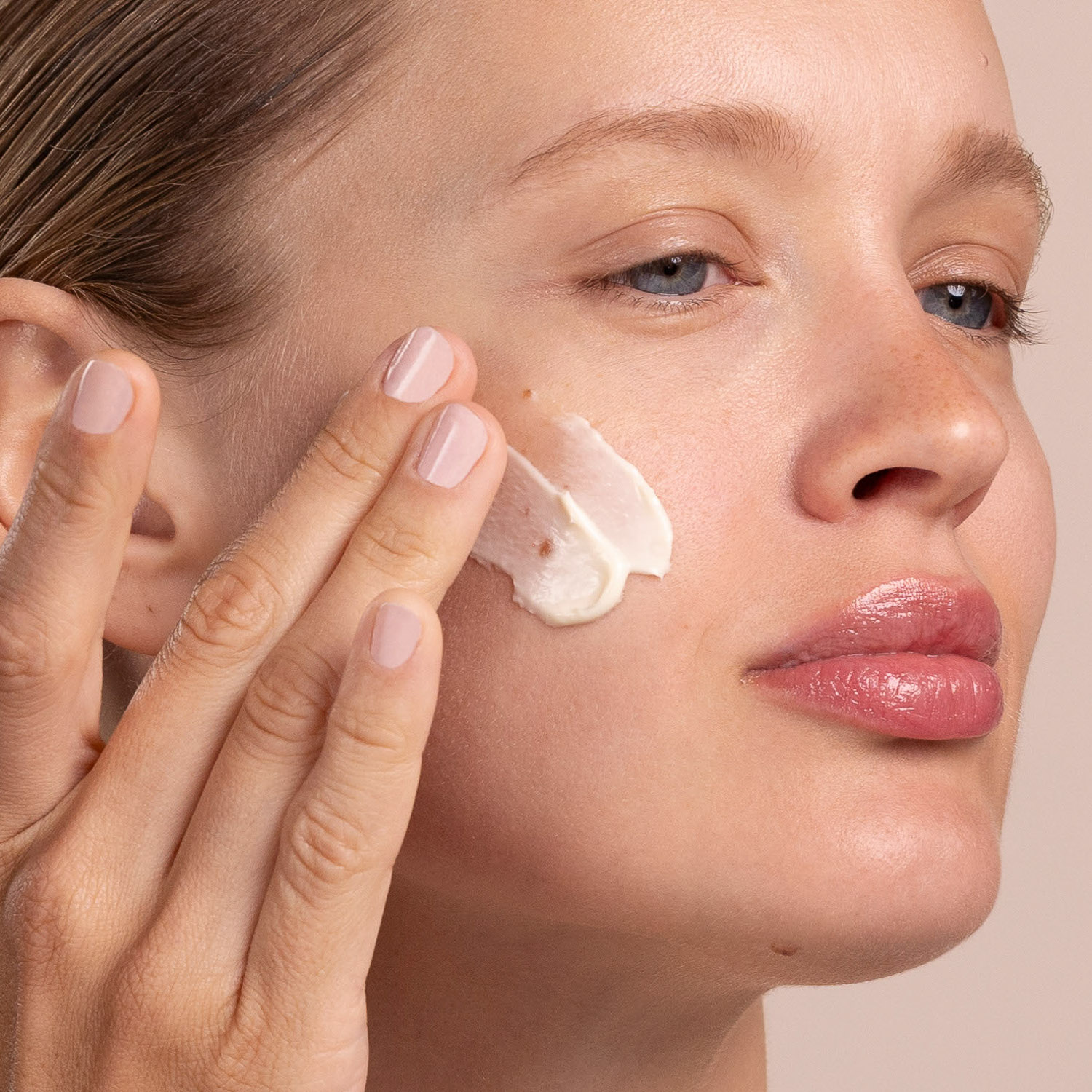 A woman with a swatch of the Eminence Organics Yellow Sweet Clover Anti-Redness Masque on her face