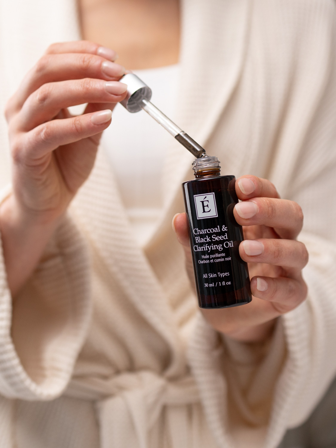 A woman holding Eminence Organics Charcoal & Black Seed Clarifying Oil