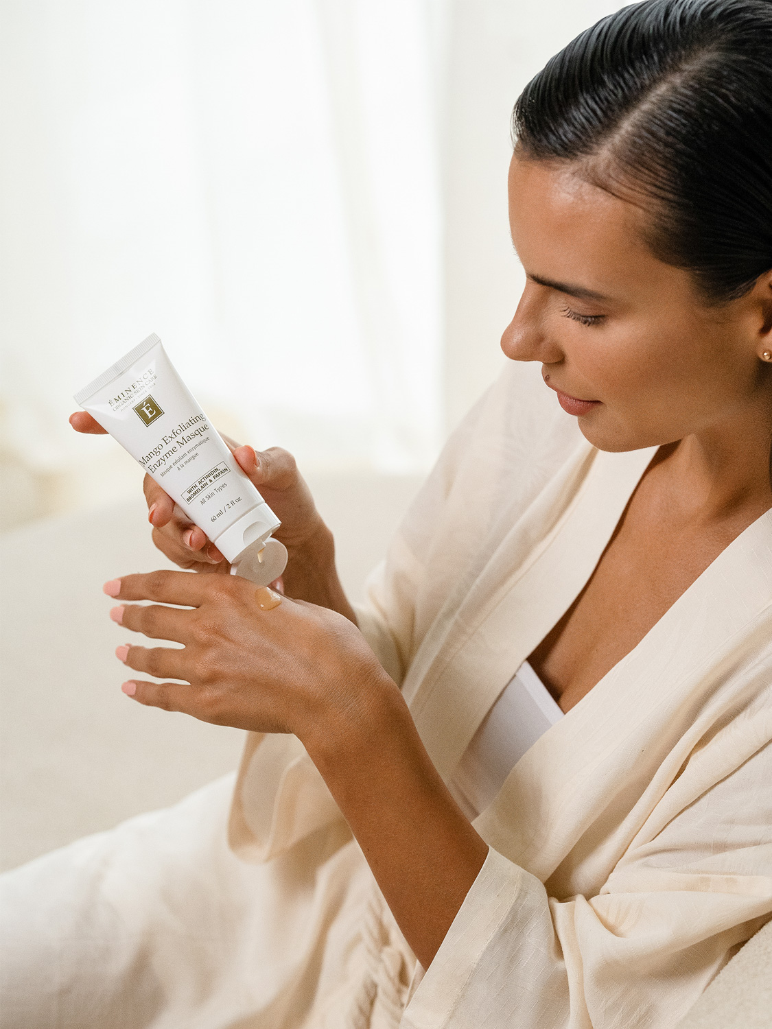 A woman applying the Eminence Organics Mango Exfoliating Enzyme Masque to the back of her hand