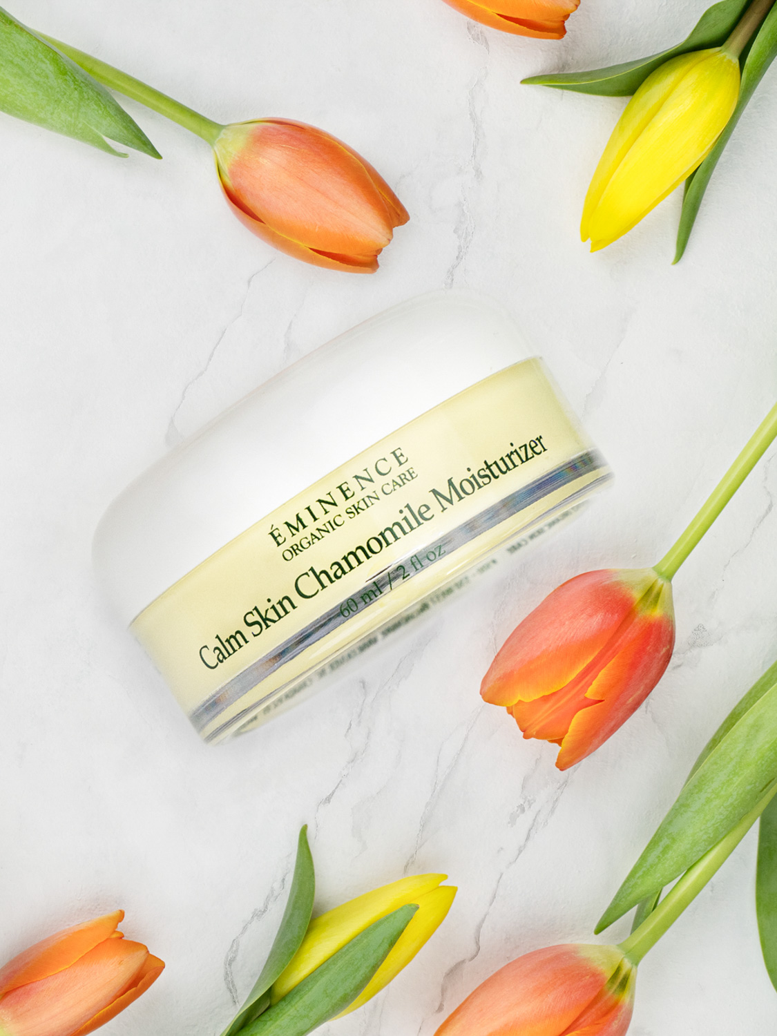 Eminence Organics Chamomile Moisturizer surrounded by flowers