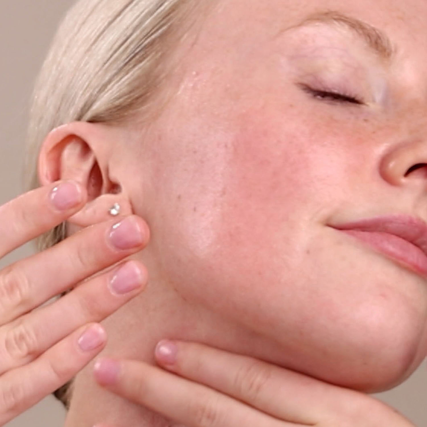 A woman applying the Eminence Organics Stone Crop Cleansing Oil on her face