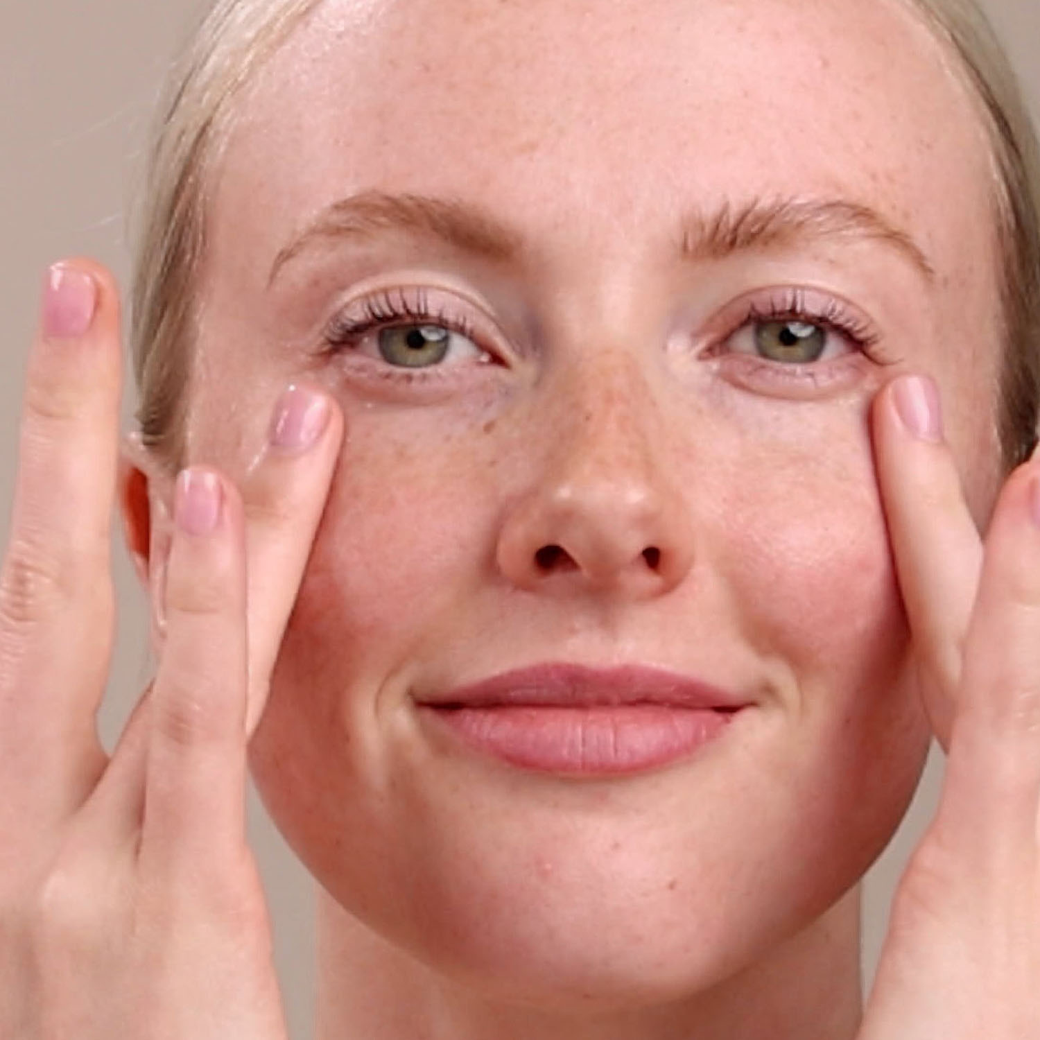 A woman applying the Eminence Organics Wild Plum Eye Cream Swatch under her eyes