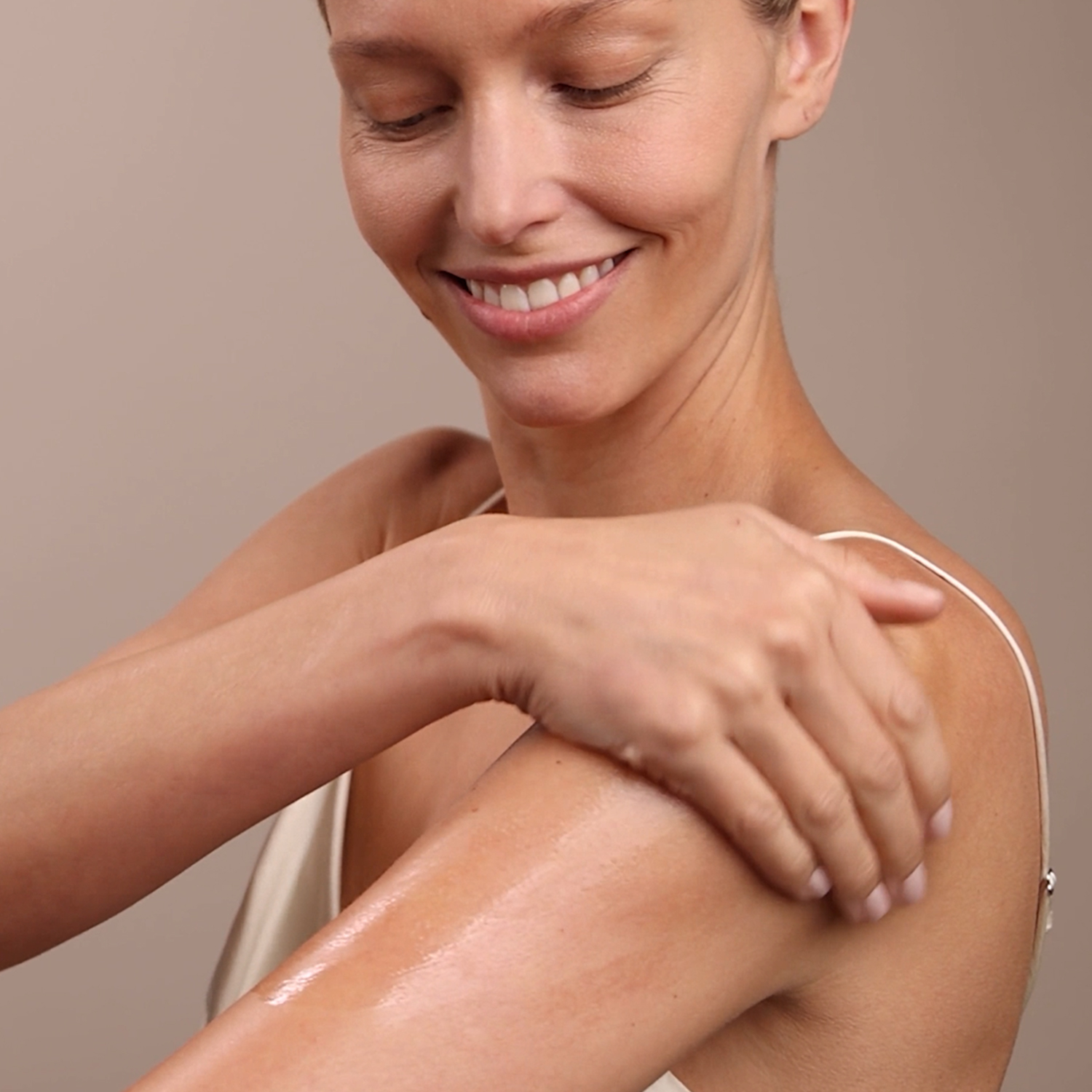 A woman applying the Eminence Organics Stone Crop Body Oil on her arm