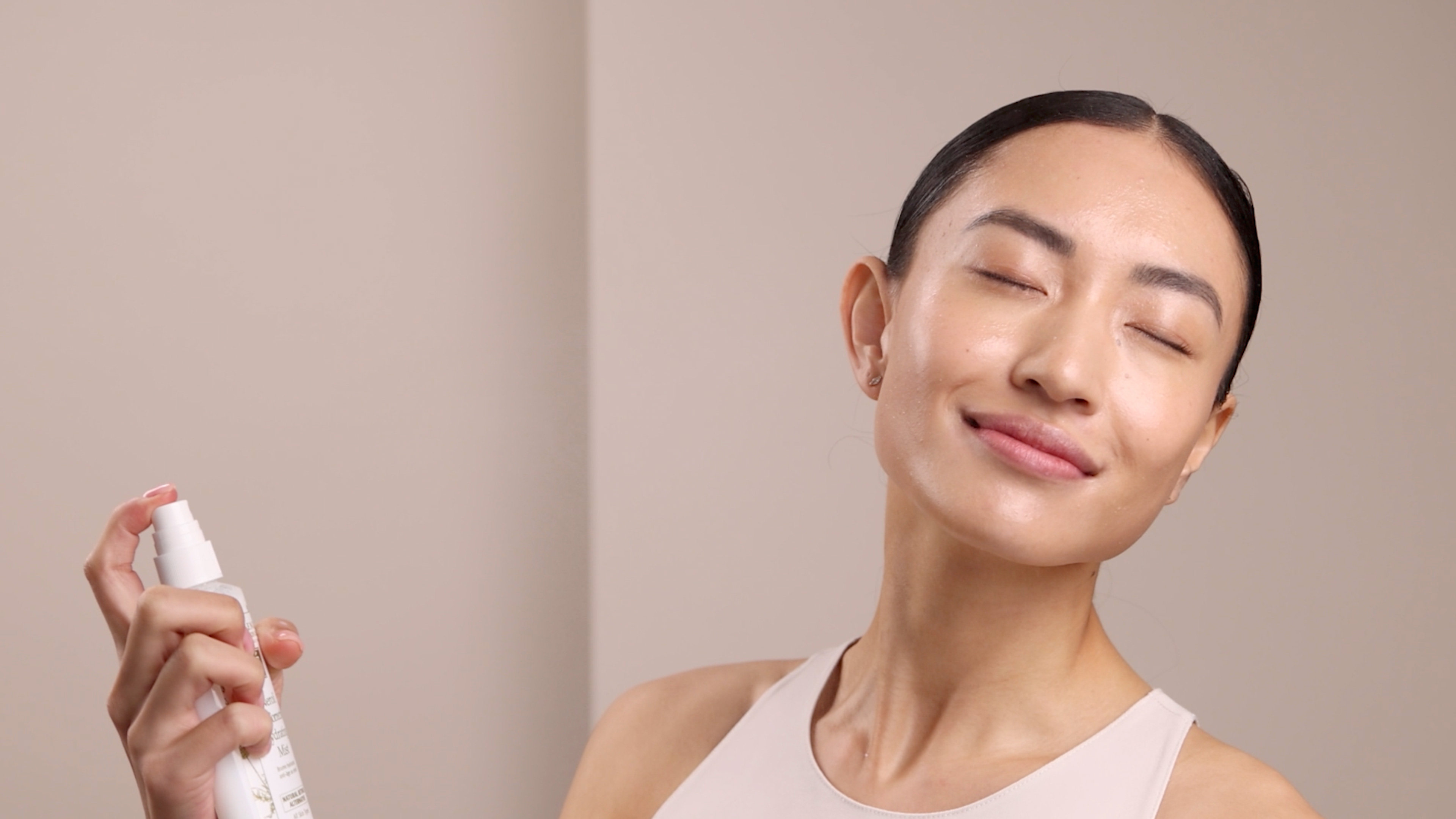 A woman spraying the Eminence Organics Neroli Age Corrective Hydrating Mist onto her face