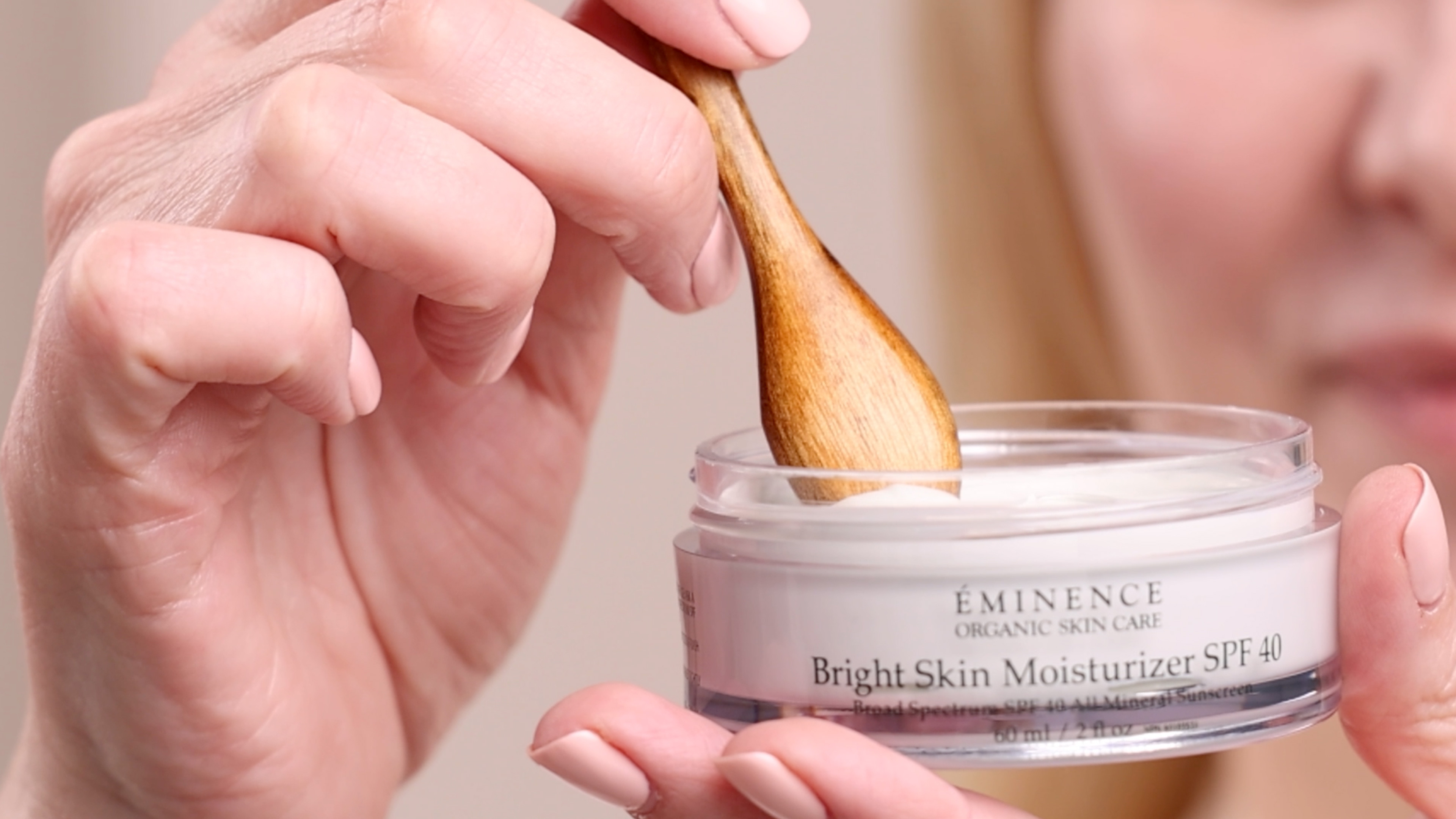 A woman holding Eminence Organics Bright Skin Moisturizer SPF 40